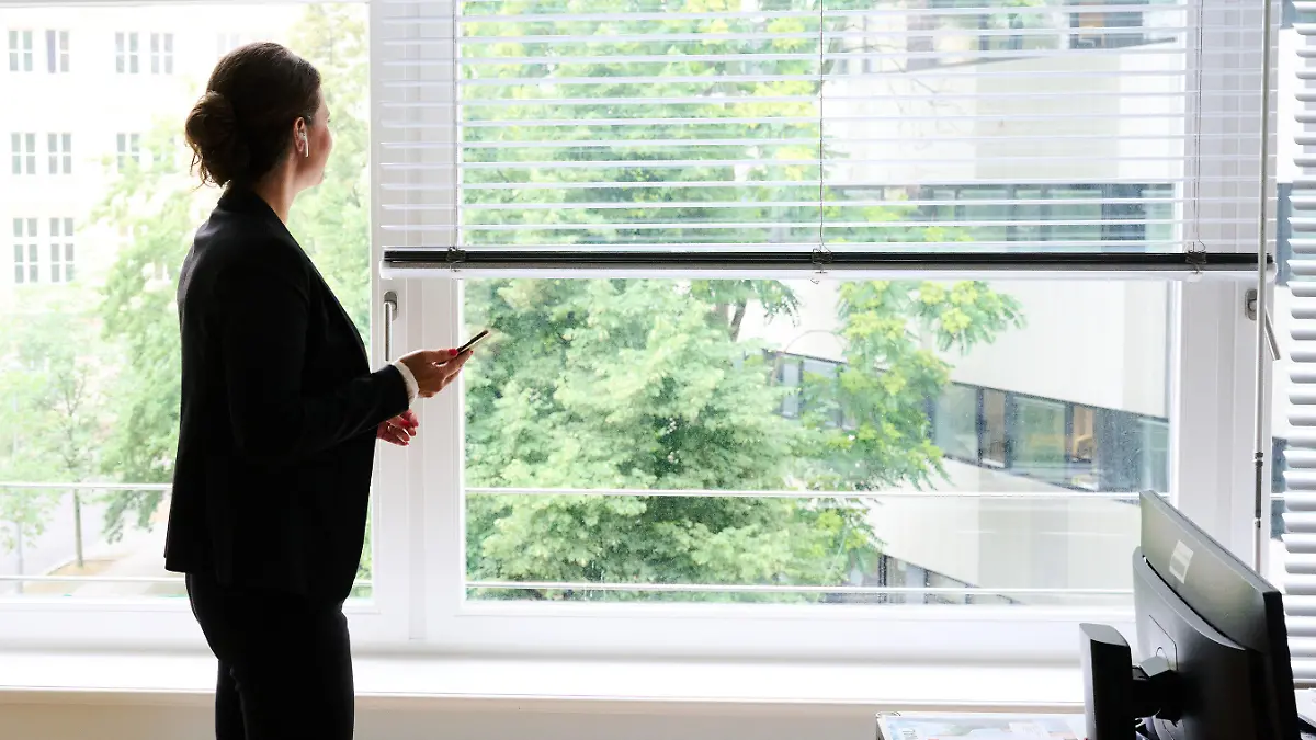 ARCHIV - 09.07.2021, Berlin: ILLUSTRATION - Eine Frau steht in einem Büro am Fenster und telefoniert über ein Headset (gestellte Szene). Der Anteil an Frauen in den Aufsichtsräten großer öffentlicher Unternehmen ist weiter leicht gestiegen, in den Vorständen gibt es dagegen im Jahresvergleich keine Bewegung. Das hat die Organisation «Frauen in die Aufsichtsräte» (Fidar) in einer Studie ermittelt, die Donnerstag (12.08.2021) vorgestellt wird. (Zu dpa «Frauenanteil in Führungsetagen öffentlicher Betriebe steigt leicht») Foto: Annette Riedl/dpa +++ dpa-Bildfunk +++
