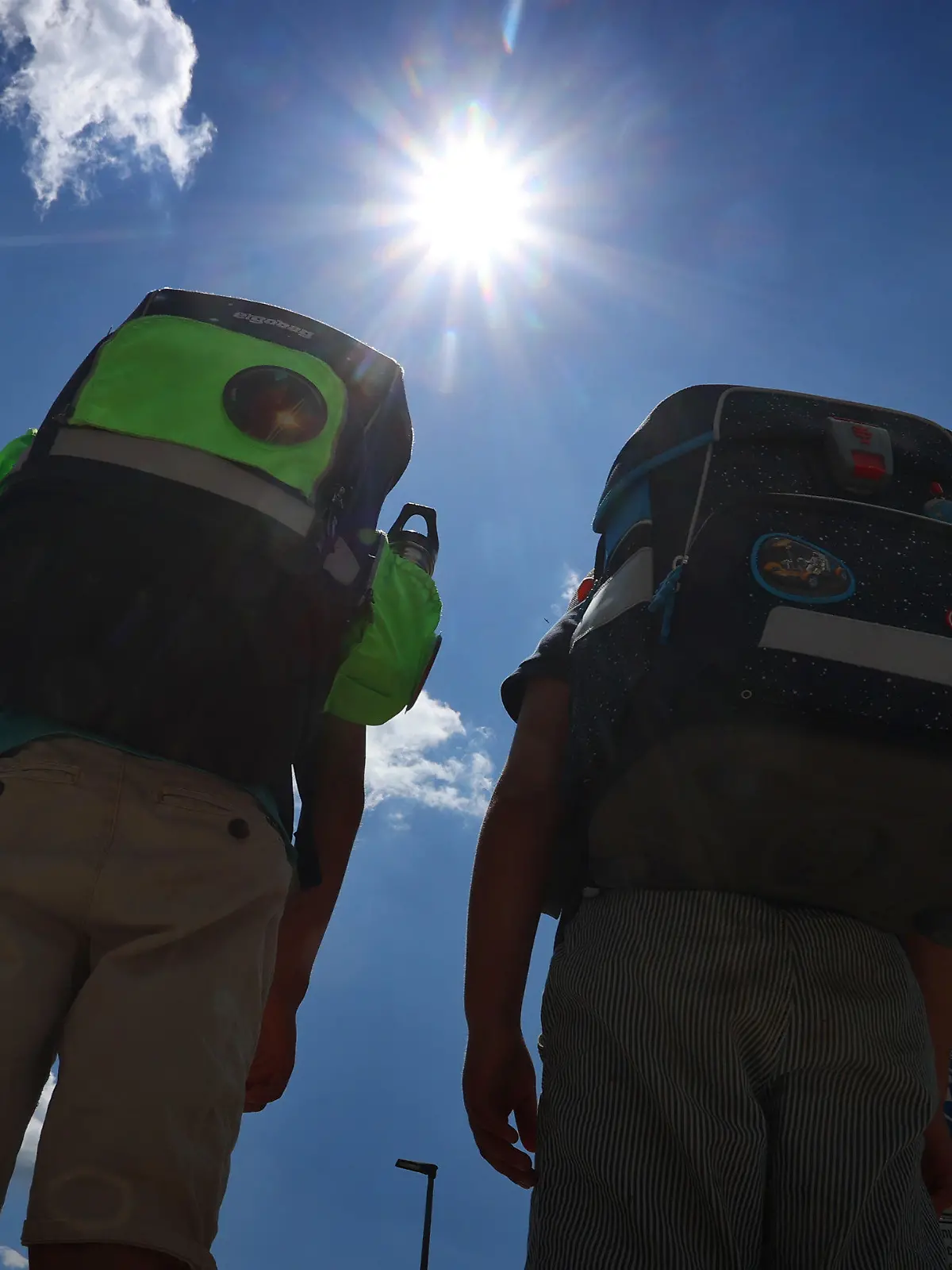 ARCHIV - 05.07.2022, Bayern, Kaufbeuren: Zwei Kinder laufen mit ihren Büchertaschen im Sonnenschein. Die Gewerkschaft Erziehung und Wissenschaft (GEW) und der Bundeselternrat haben einheitliche Regeln für hitzefrei an Schulen in Deutschland gefordert. (zu dpa: «Verbände für einheitliche Hitzefrei-Regeln und mehr Schutz in Schulen») Foto: Karl-Josef Hildenbrand/dpa +++ dpa-Bildfunk +++
