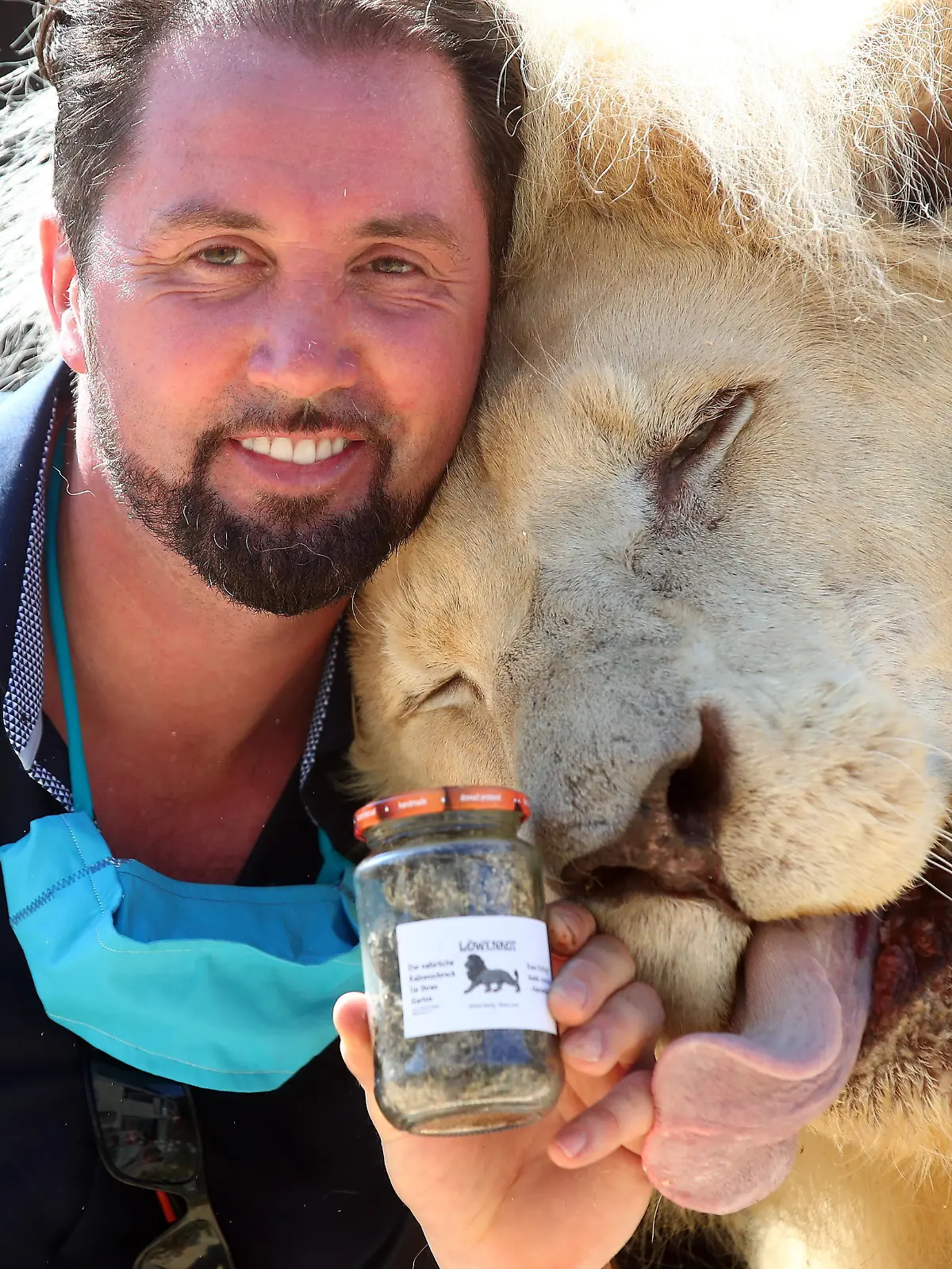 Lion tamer Martin Lacey poses with Lion King Tonga and a glass of lion droppings, which Circus Krone sells amid the coronavirus disease (COVID-19) pandemic, in Munich, Germany, August 10, 2020. Circus Krone is selling the product to be used as a household remedy to keep other wild animals away and sales should make up for the financial losses the circus suffered during the Corona crisis. REUTERS/Michael Dalder