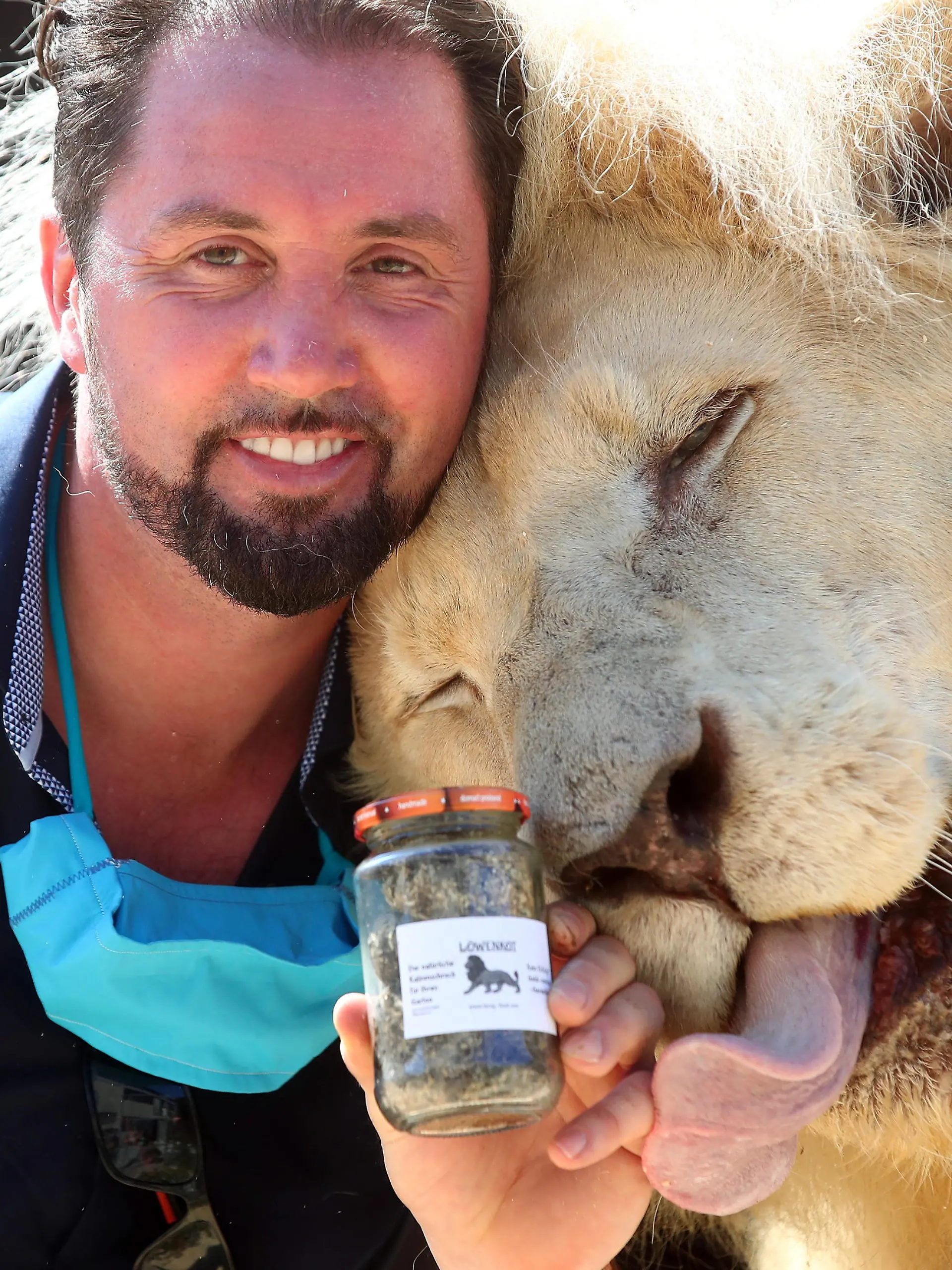 Lion tamer Martin Lacey poses with Lion King Tonga and a glass of lion droppings, which Circus Krone sells amid the coronavirus disease (COVID-19) pandemic, in Munich, Germany, August 10, 2020. Circus Krone is selling the product to be used as a household remedy to keep other wild animals away and sales should make up for the financial losses the circus suffered during the Corona crisis. REUTERS/Michael Dalder