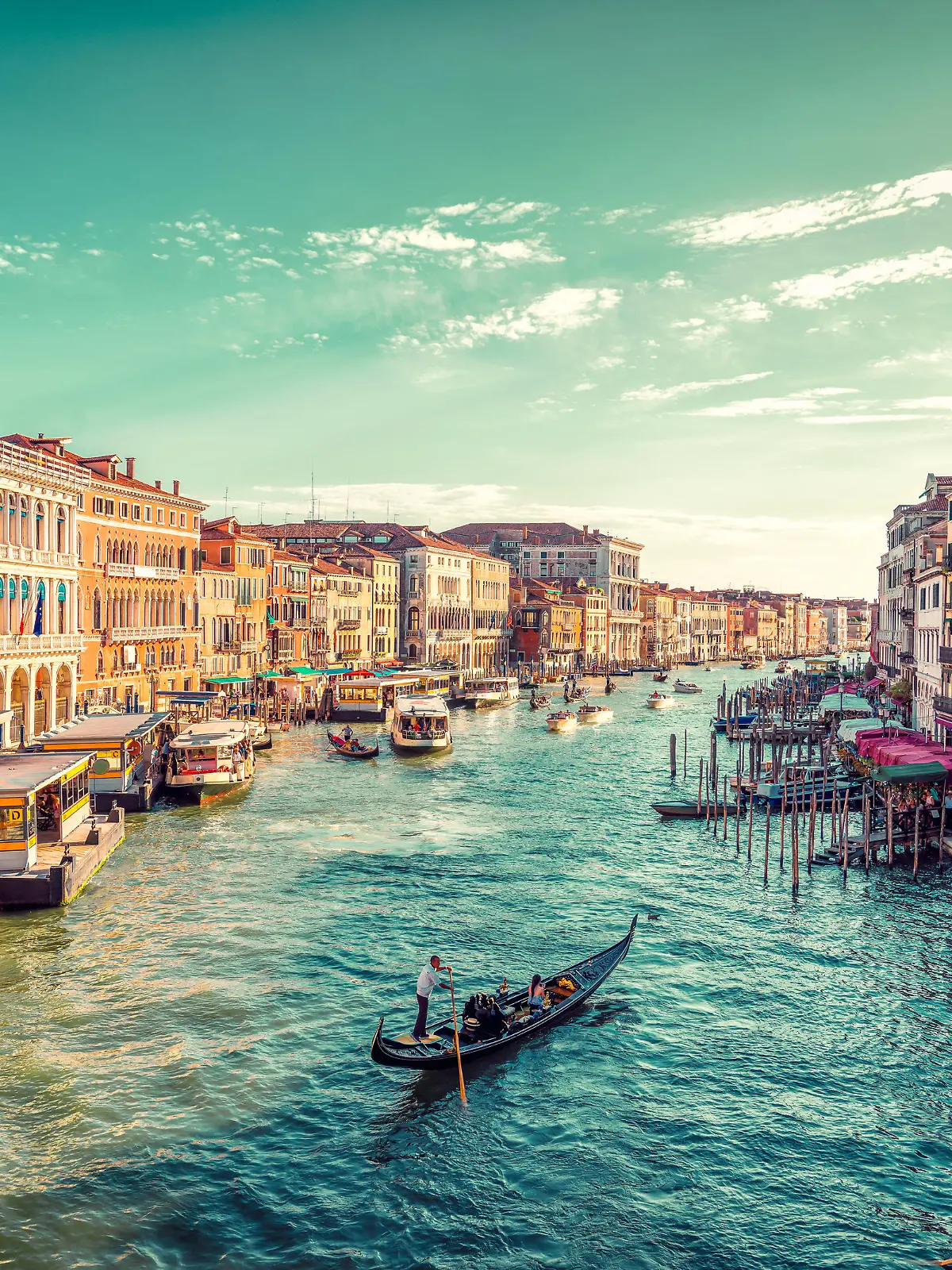 A gondolier paddles towards the sunset in Venice's Grand Canal. Photo taken from the famous Rialto Bridge