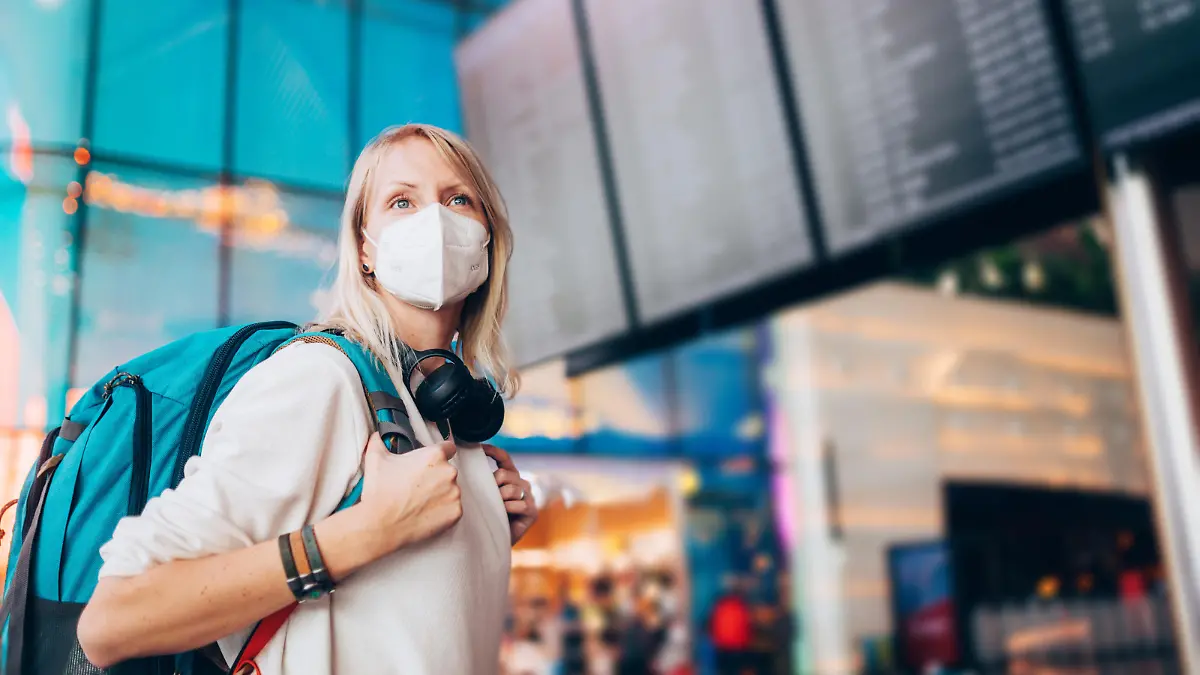 Portrait of a young woman checks the arrivals and departures board at the airport. She wears a face mask for protection during a Coronavirus pandemic.
New normal lifestyle for public transport after Covid-19
