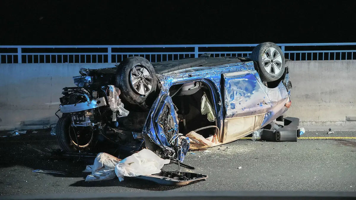 26.06.2022, Hessen, Wiesbaden: Ein Wrack liegt auf dem Dach auf der Schiersteiner Brücke. Zwei Menschen sind bei einem Unfall auf der A643 ums Leben gekommen. Ein 63-jähriger Autofahrer hatte nach Angaben der Polizei am späten Samstagabend die Kontrolle über seinen Wagen verloren, als er mit überhöhter Geschwindigkeit in einem Tempo-40-Bereich auf der Brücke unterwegs war. (zu dpa: «Zwei Tote bei Frontalzusammenstoß auf A643 in Wiesbaden») Foto: Luca Simon/Wiesbaden112.de/dpa +++ dpa-Bildfunk +++