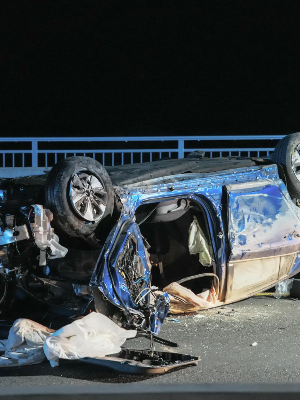 26.06.2022, Hessen, Wiesbaden: Ein Wrack liegt auf dem Dach auf der Schiersteiner Brücke. Zwei Menschen sind bei einem Unfall auf der A643 ums Leben gekommen. Ein 63-jähriger Autofahrer hatte nach Angaben der Polizei am späten Samstagabend die Kontrolle über seinen Wagen verloren, als er mit überhöhter Geschwindigkeit in einem Tempo-40-Bereich auf der Brücke unterwegs war. (zu dpa: «Zwei Tote bei Frontalzusammenstoß auf A643 in Wiesbaden») Foto: Luca Simon/Wiesbaden112.de/dpa +++ dpa-Bildfunk +++