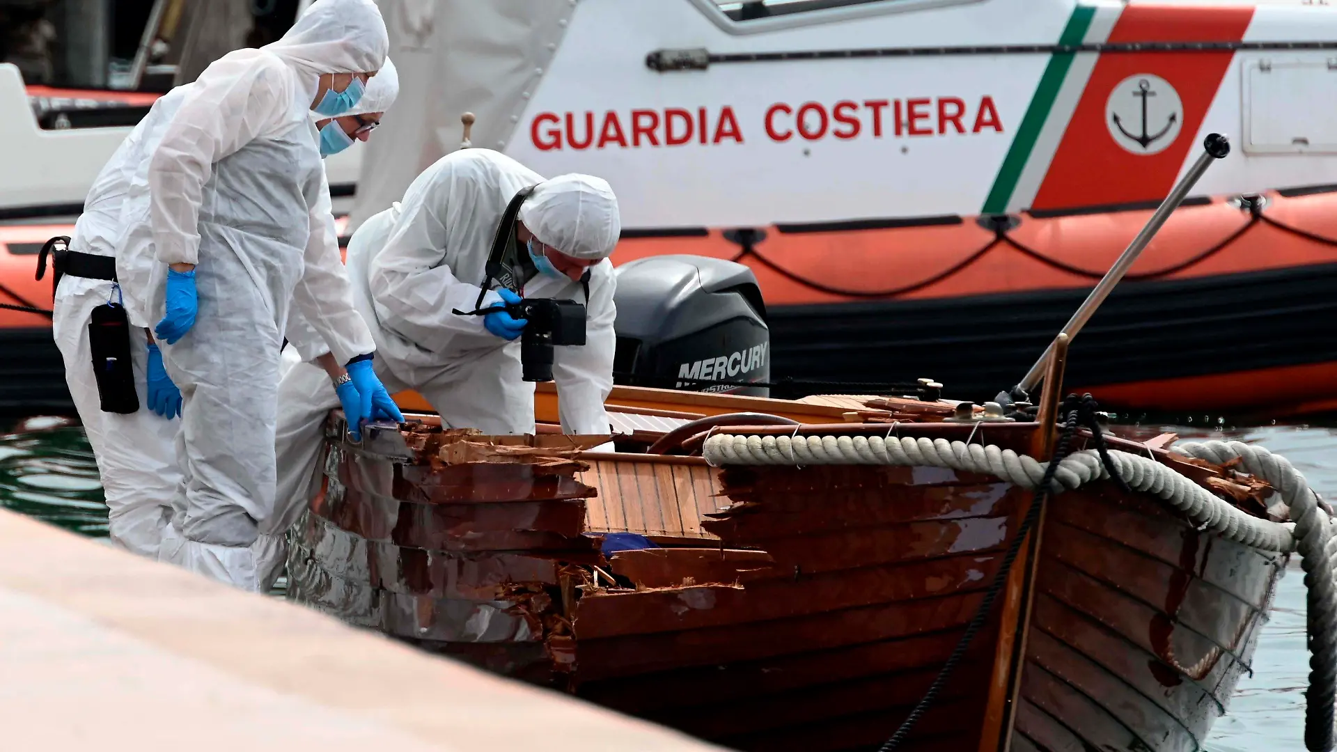 ARCHIV - 20.06.2021, Italien, Salo: Forensiker begutachten den Schaden an einem Boot im Hafen von Salo. Zwei Münchner sollen in einer Nacht im Juni ein Motorboot gesteuert haben, das mit einem kleinen Boot kollidierte. Dabei starben die beiden Insassen des kleinen Bootes. (zu dpa: «Urteilsverkündung im Gardasee-Prozess mit zwei angeklagten Deutschen») Foto: Gabriele Strada/AP/dpa +++ dpa-Bildfunk +++