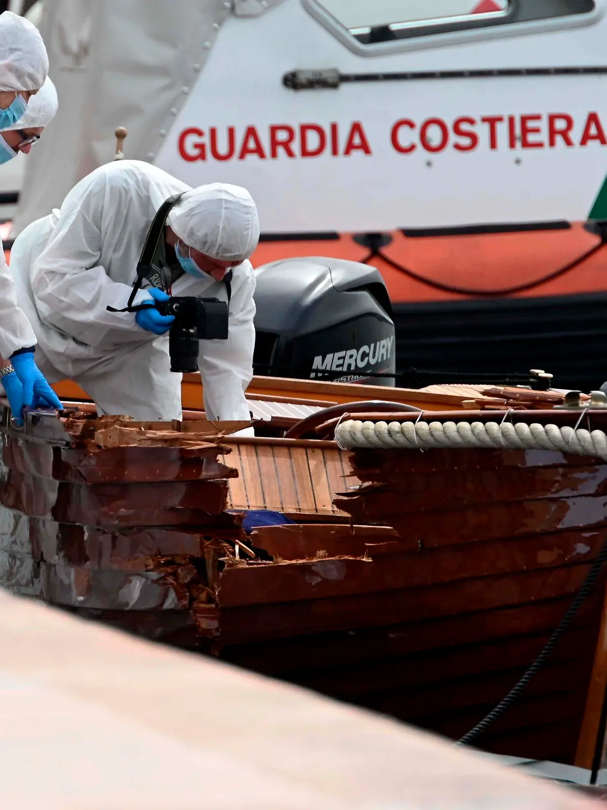 ARCHIV - 20.06.2021, Italien, Salo: Forensiker begutachten den Schaden an einem Boot im Hafen von Salo. Zwei Münchner sollen in einer Nacht im Juni ein Motorboot gesteuert haben, das mit einem kleinen Boot kollidierte. Dabei starben die beiden Insassen des kleinen Bootes. (zu dpa: «Urteilsverkündung im Gardasee-Prozess mit zwei angeklagten Deutschen») Foto: Gabriele Strada/AP/dpa +++ dpa-Bildfunk +++