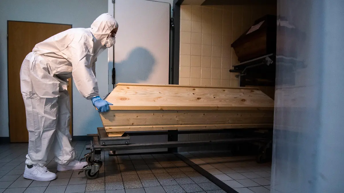 13.01.2021, Niedersachsen, Celle: Mitarbeiter Niklas Grube schiebt im Krematorium «Die Feuerbestattungen Celle» einen Sarg in eine Kühlkammer, in der Särge von Verstorbenen stehen, die mit oder an dem Corona-Virus gestorben sind. Das Krematorium in Celle verzeichnet seit November 2020 einen Anstieg von Einäscherungen von Corona-Toten. Foto: Julian Stratenschulte/dpa +++ dpa-Bildfunk +++