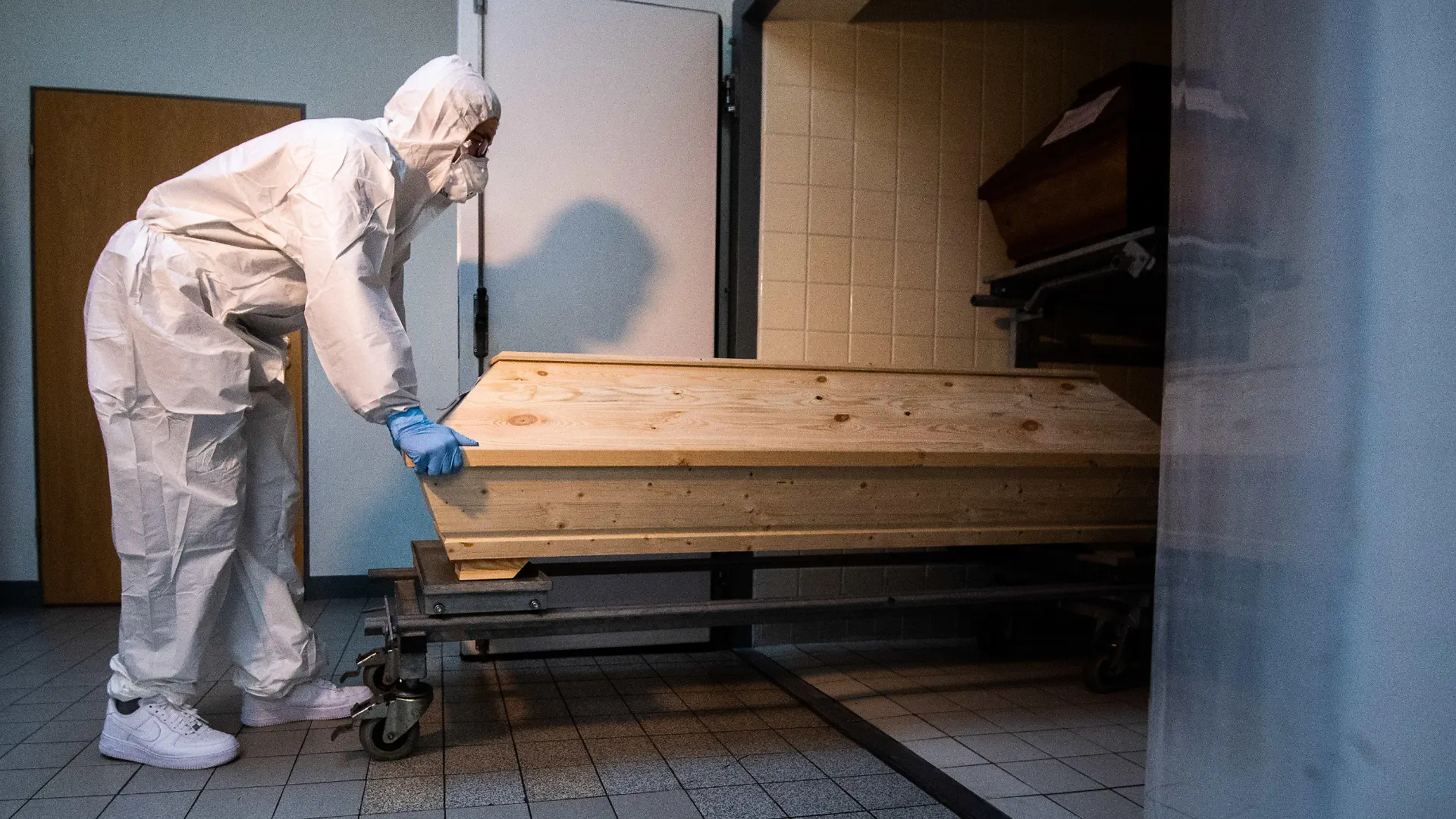 13.01.2021, Niedersachsen, Celle: Mitarbeiter Niklas Grube schiebt im Krematorium «Die Feuerbestattungen Celle» einen Sarg in eine Kühlkammer, in der Särge von Verstorbenen stehen, die mit oder an dem Corona-Virus gestorben sind. Das Krematorium in Celle verzeichnet seit November 2020 einen Anstieg von Einäscherungen von Corona-Toten. Foto: Julian Stratenschulte/dpa +++ dpa-Bildfunk +++