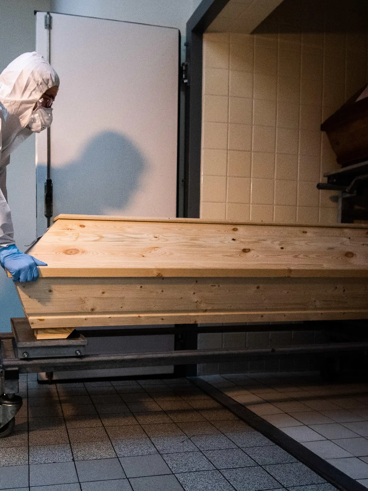 13.01.2021, Niedersachsen, Celle: Mitarbeiter Niklas Grube schiebt im Krematorium «Die Feuerbestattungen Celle» einen Sarg in eine Kühlkammer, in der Särge von Verstorbenen stehen, die mit oder an dem Corona-Virus gestorben sind. Das Krematorium in Celle verzeichnet seit November 2020 einen Anstieg von Einäscherungen von Corona-Toten. Foto: Julian Stratenschulte/dpa +++ dpa-Bildfunk +++