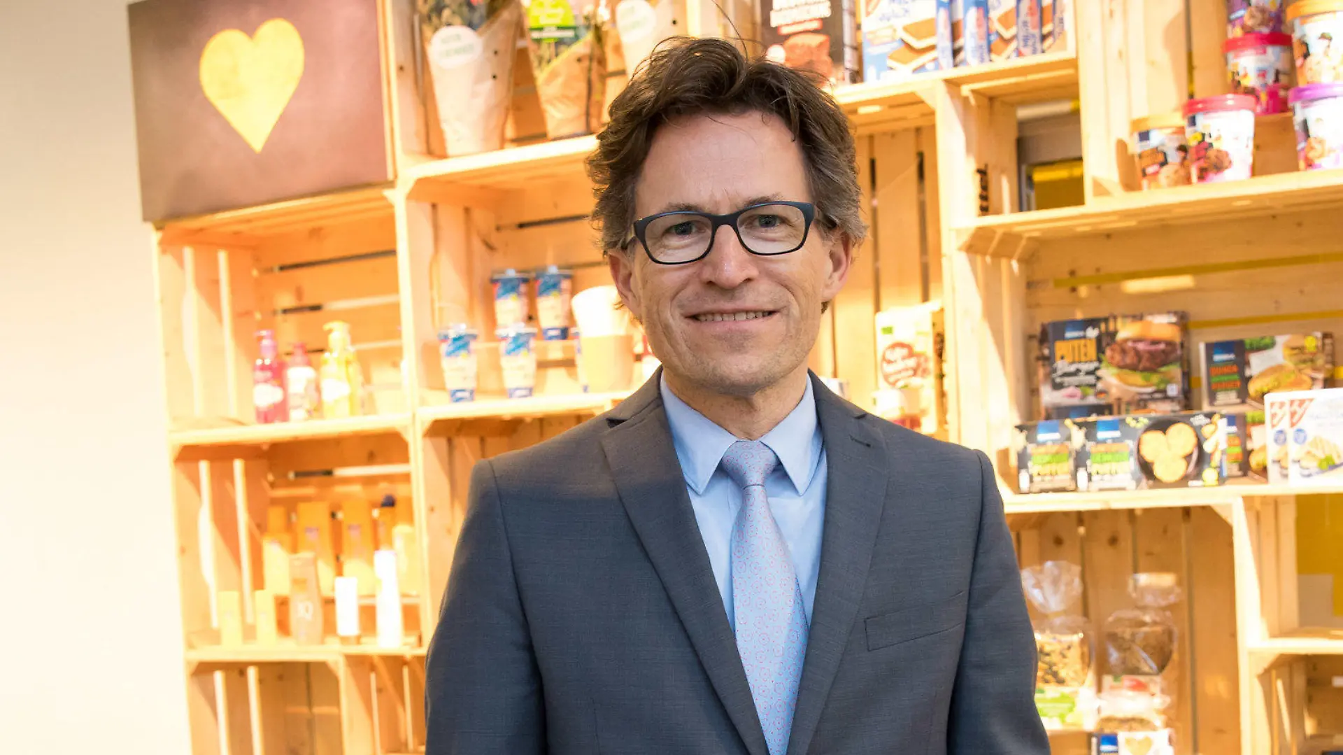 ARCHIV - 17.04.2018, Hamburg: Markus Mosa, Vorstandsvorsitzender der EDEKA AG, steht im Ideenlabor der Konzernzentrale vor einer dekorierten Wand mit Lebensmitteln und Produkten der Edeka Eigenmarke. (zu dpa «Edeka beklagt Preistreibereien globaler Markenhersteller») Foto: Christian Charisius/dpa +++ dpa-Bildfunk +++