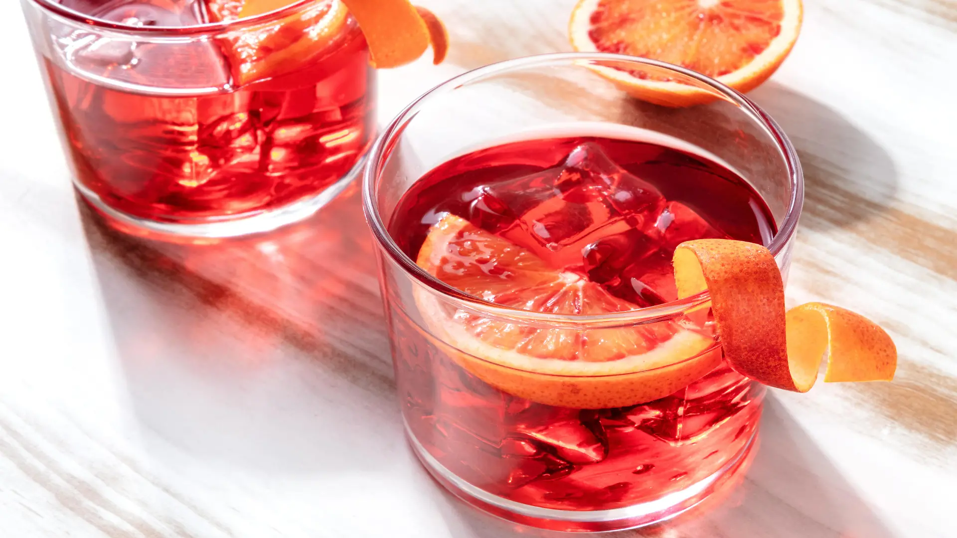 Negroni cocktail with blood oranges, on a wooden background