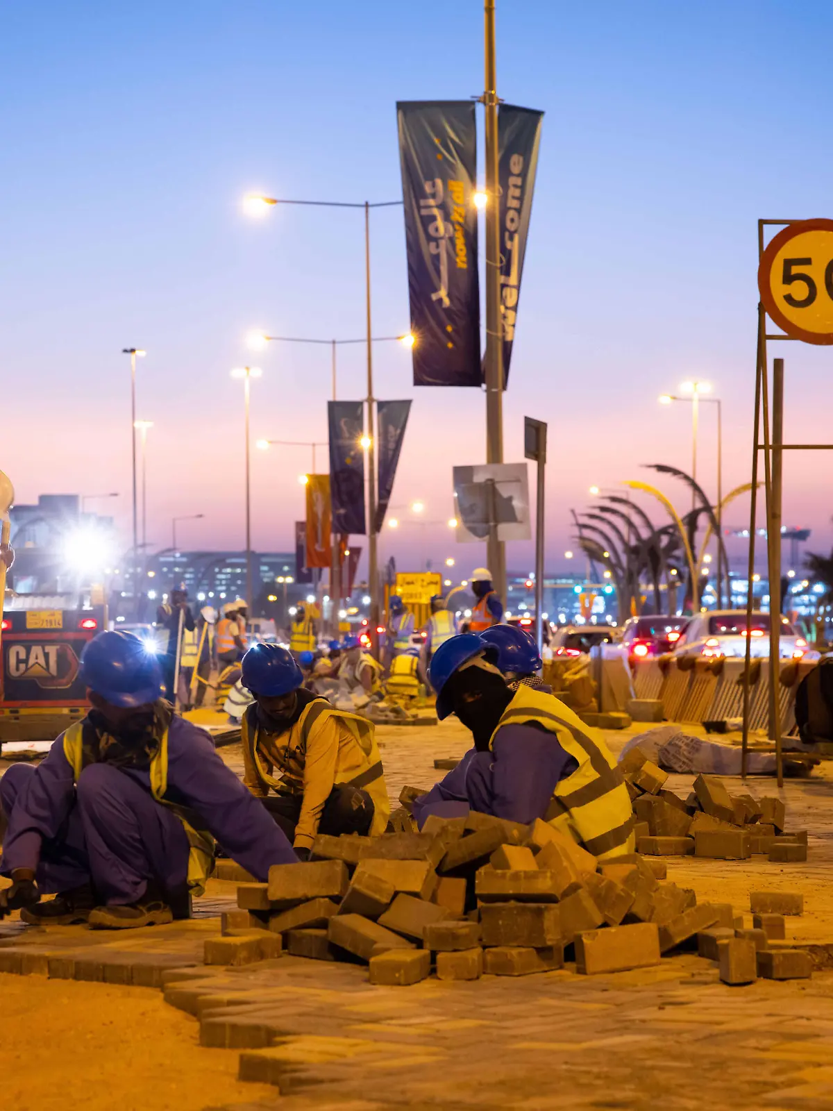 Arbeiter pflastern kurz nach dem Sonnenuntergang im Licht von Laternen einen Weg zwischen den Fahrbahnen an der Promenade Corniche. In Doha finden am 31. März der Fifa-Kongress und am 1. April die Auslosung für die Fußball-WM 2022 in Katar statt.