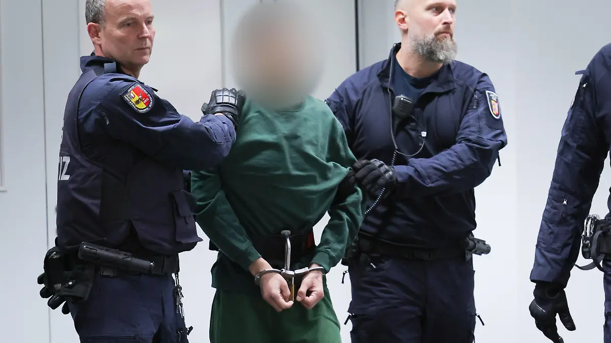 07.07.2023, Schleswig-Holstein, Itzehoe: Der Angeklagte Ibrahim A. wird von Justizbeamten an seinen Platz im Gerichtssaal im China Logistic Center gebracht. Am Freitag begann vor dem Landgericht Itzehoe der Prozess gegen Ibrahim A. wegen der tödlichen Messerattacke in einem Regionalzug im schleswig-holsteinischen Brokstedt am 25. Januar 2023. Foto: Christian Charisius/dpa-POOL/dpa - ACHTUNG: Person(en) wurde(n) aus rechtlichen Gründen gepixelt +++ dpa-Bildfunk +++