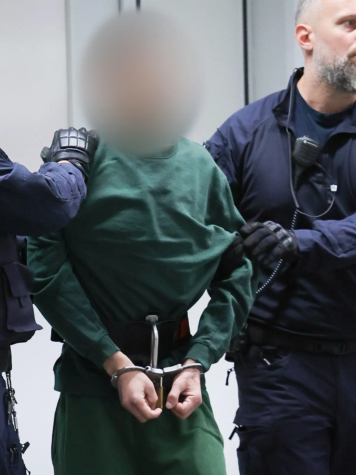 07.07.2023, Schleswig-Holstein, Itzehoe: Der Angeklagte Ibrahim A. wird von Justizbeamten an seinen Platz im Gerichtssaal im China Logistic Center gebracht. Am Freitag begann vor dem Landgericht Itzehoe der Prozess gegen Ibrahim A. wegen der tödlichen Messerattacke in einem Regionalzug im schleswig-holsteinischen Brokstedt am 25. Januar 2023. Foto: Christian Charisius/dpa-POOL/dpa - ACHTUNG: Person(en) wurde(n) aus rechtlichen Gründen gepixelt +++ dpa-Bildfunk +++