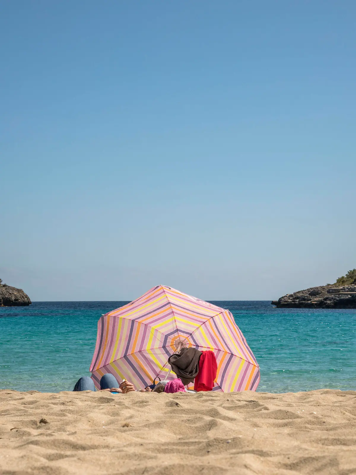 dpatopbilder - 25.03.2021, Spanien, Cala D'or: Zwei Personen liegen unter einem Sonnenschirm an einem Strand auf Mallorca. Angesichts der Corona-Pandemie sollen sich Flugpassagiere vor dem Start nach Deutschland künftig generell testen lassen müssen - und zwar ab diesem Sonntag um 0.00 Uhr. Foto: John-Patrick Morarescu/ZUMA Wire/dpa +++ dpa-Bildfunk +++