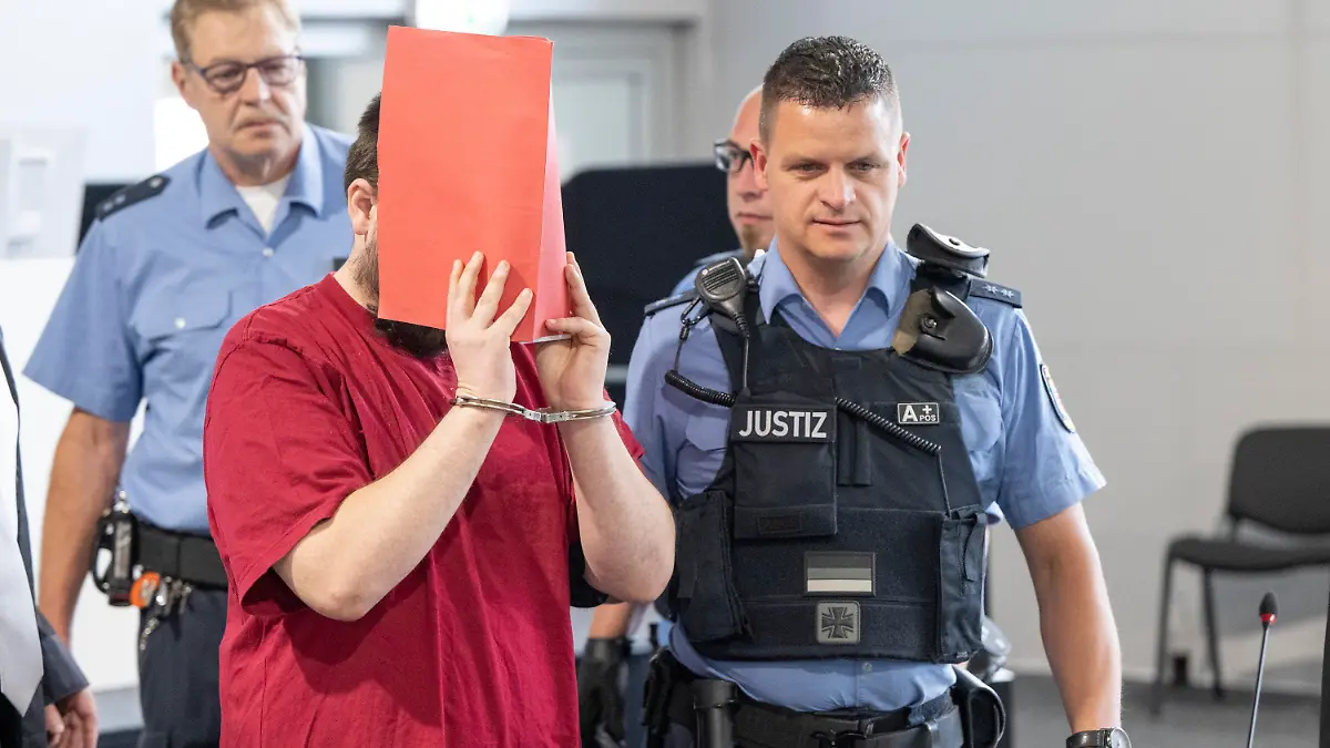19.06.2023, Hessen, Gießen: Der Angeklagte (M) wird von Justizwachtmeistern in den Verhandlungssaal gebracht. Die Staatsanwaltschaft wirft dem zum Tatzeitpunkt 30-Jährigen vor, die 14 Jahre alte Schülerin Ayleen aus dem südbadischen Gottenheim in Baden-Württemberg im Juli 2022 umgebracht zu haben. Foto: Boris Roessler/dpa +++ dpa-Bildfunk +++