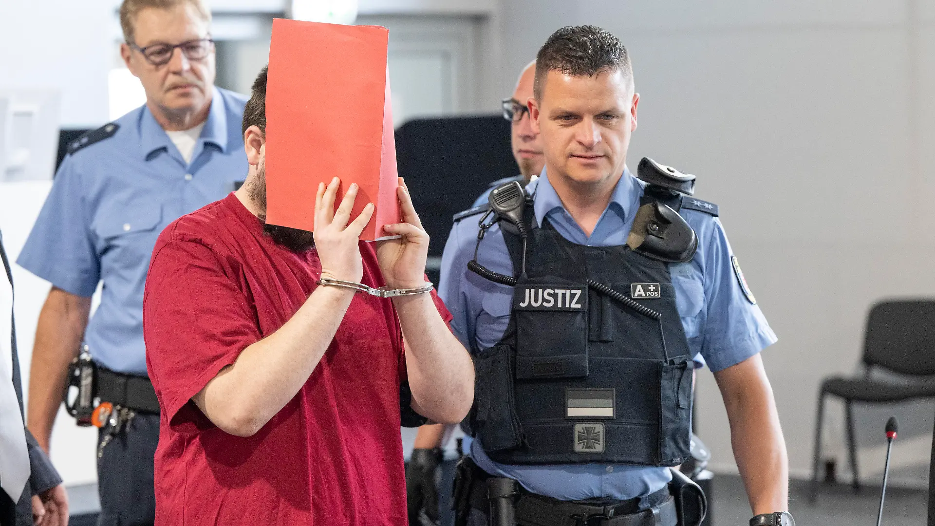 19.06.2023, Hessen, Gießen: Der Angeklagte (M) wird von Justizwachtmeistern in den Verhandlungssaal gebracht. Die Staatsanwaltschaft wirft dem zum Tatzeitpunkt 30-Jährigen vor, die 14 Jahre alte Schülerin Ayleen aus dem südbadischen Gottenheim in Baden-Württemberg im Juli 2022 umgebracht zu haben. Foto: Boris Roessler/dpa +++ dpa-Bildfunk +++