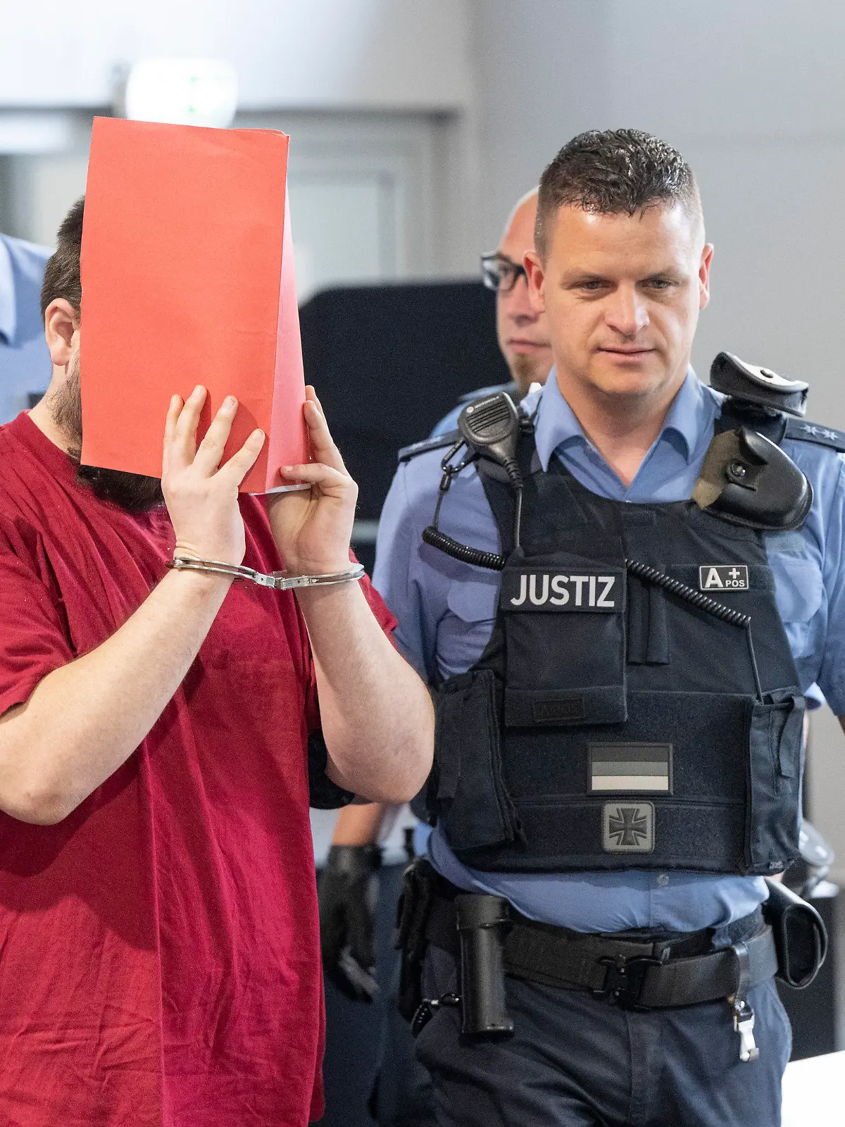 19.06.2023, Hessen, Gießen: Der Angeklagte (M) wird von Justizwachtmeistern in den Verhandlungssaal gebracht. Die Staatsanwaltschaft wirft dem zum Tatzeitpunkt 30-Jährigen vor, die 14 Jahre alte Schülerin Ayleen aus dem südbadischen Gottenheim in Baden-Württemberg im Juli 2022 umgebracht zu haben. Foto: Boris Roessler/dpa +++ dpa-Bildfunk +++