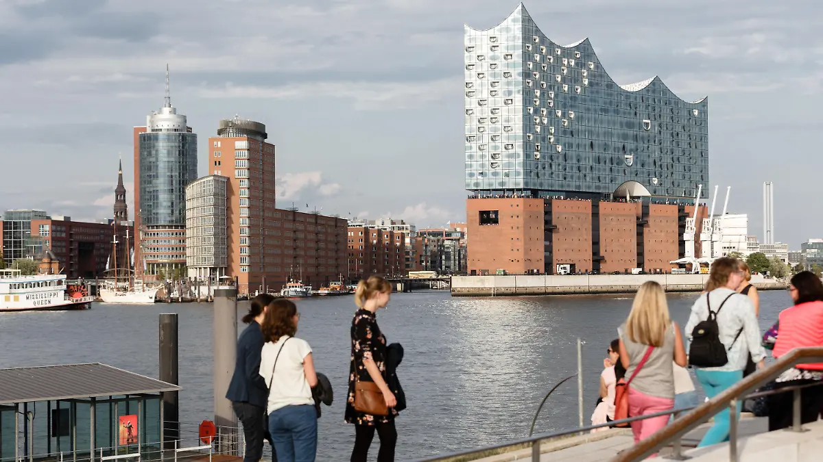 ARCHIV - 14.08.2019, Hamburg: Touristen sitzen am südlichen Elbufer, am Anleger «König der Löwen», und betrachten das Hamburg-Panorama, Blickrichtung Elbphilharmonie. (Zu dpa: «Hamburger Tourismus gibt sich zum Ferienbeginn optimistisch») Foto: Markus Scholz/dpa +++ dpa-Bildfunk +++