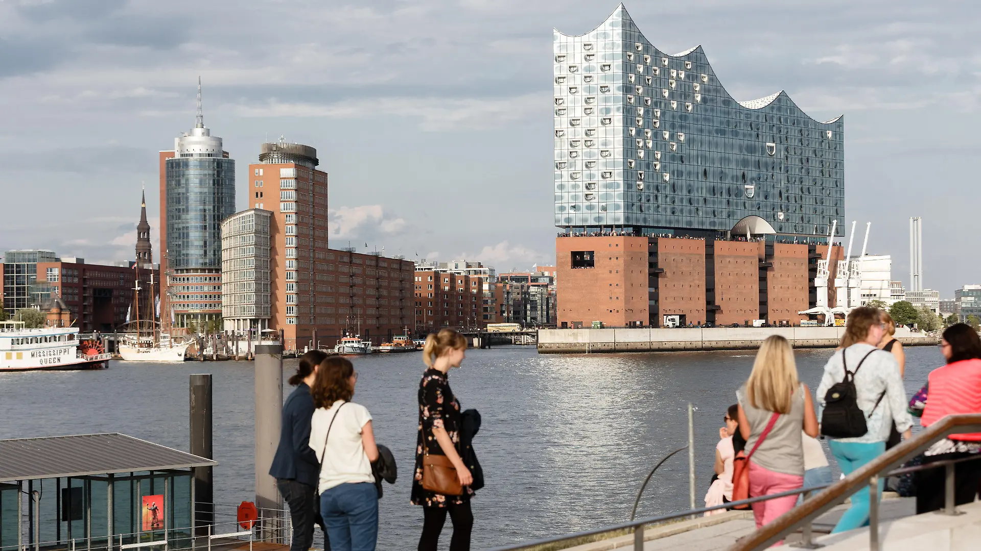 ARCHIV - 14.08.2019, Hamburg: Touristen sitzen am südlichen Elbufer, am Anleger «König der Löwen», und betrachten das Hamburg-Panorama, Blickrichtung Elbphilharmonie. (Zu dpa: «Hamburger Tourismus gibt sich zum Ferienbeginn optimistisch») Foto: Markus Scholz/dpa +++ dpa-Bildfunk +++