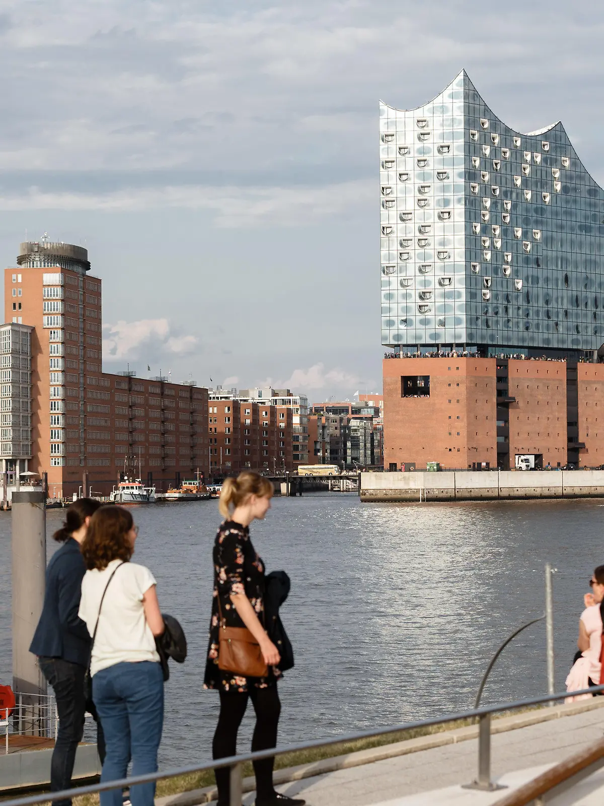 ARCHIV - 14.08.2019, Hamburg: Touristen sitzen am südlichen Elbufer, am Anleger «König der Löwen», und betrachten das Hamburg-Panorama, Blickrichtung Elbphilharmonie. (Zu dpa: «Hamburger Tourismus gibt sich zum Ferienbeginn optimistisch») Foto: Markus Scholz/dpa +++ dpa-Bildfunk +++
