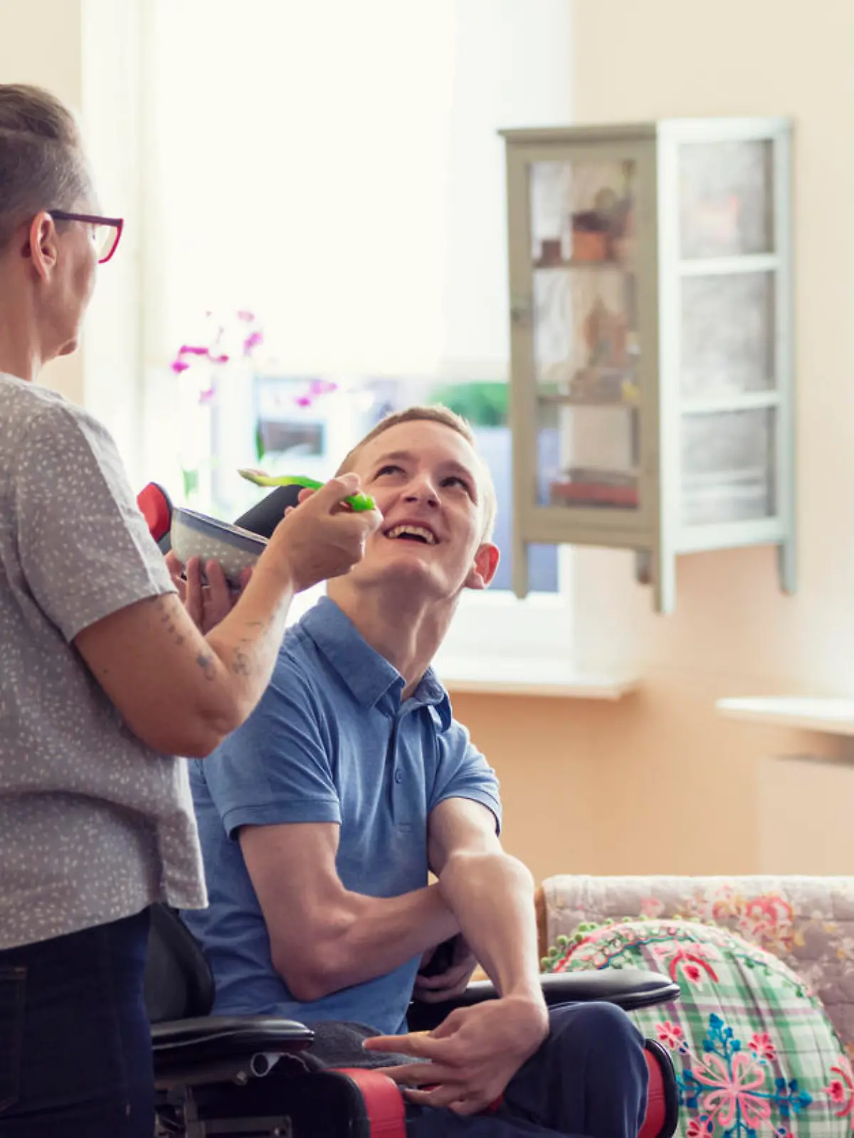 Color image of a real life young physically impaired Cerebral Palsy patient being fed by his mother.