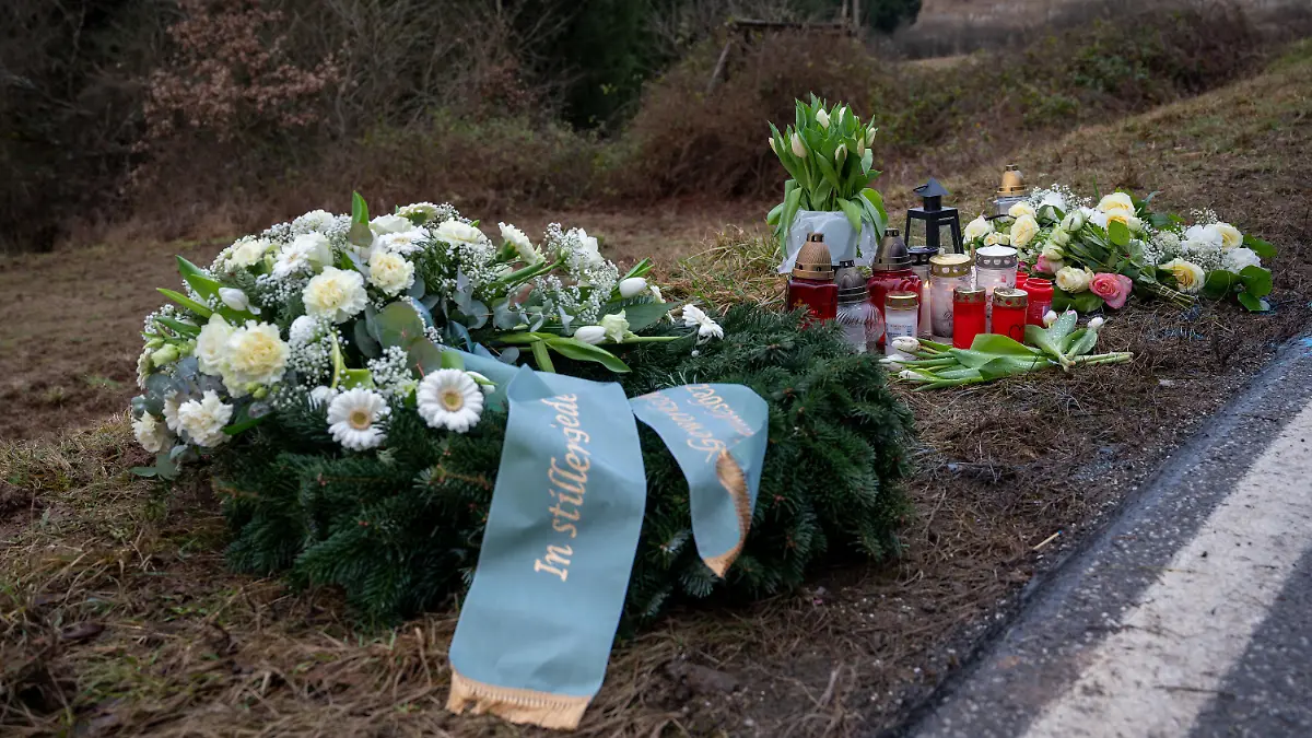 02.02.2022, Rheinland-Pfalz, Kusel: Ein Kranz sowie Blumen und Kerzen liegen am Tatort an der Kreisstraße 22 bei Ulmet (Rheinland-Pfalz) zum Gedenken. Am Montag wurden in der Nähe bei Ulmet eine Polizistin und ein Polizist im Dienst getötet. Foto: Harald Tittel/dpa +++ dpa-Bildfunk +++