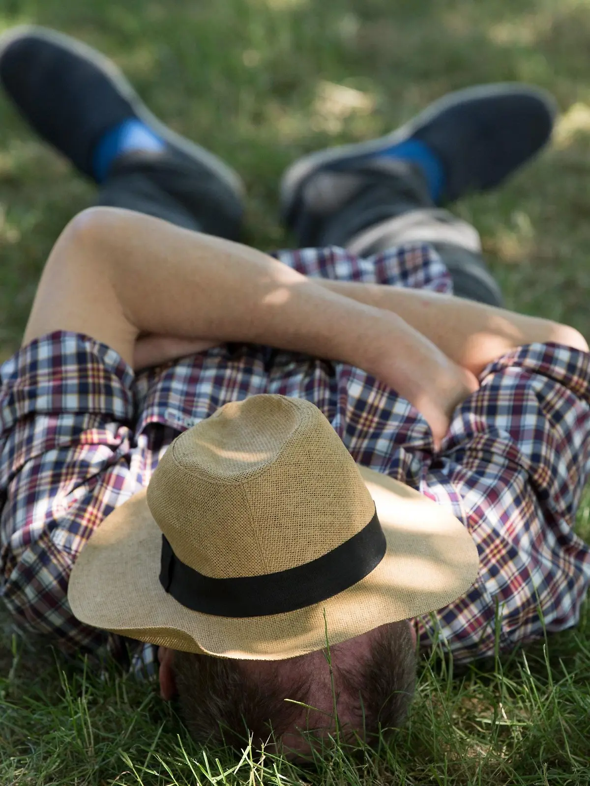 ARCHIV - 07.06.2018, Sachsen, Dresden: Ein Mann  mit einem Sonnenhut auf dem Gesicht  liegt auf einer Wiese im Schatten und ruht sich aus.   (zu dpa "DGB fordert wegen Hitze «Siesta» für Arbeitnehmer") Foto: Sebastian Kahnert/zb/dpa +++ dpa-Bildfunk +++