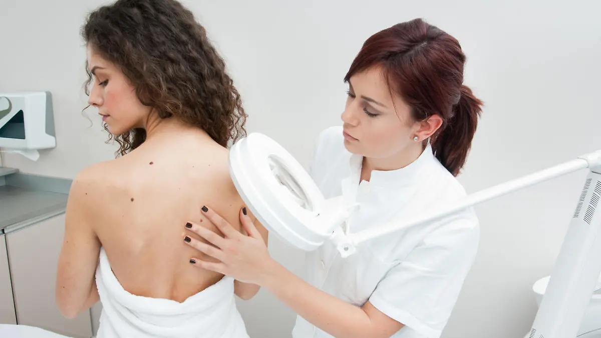 dermatologist doctor inspecting woman skin for moles and melanoma