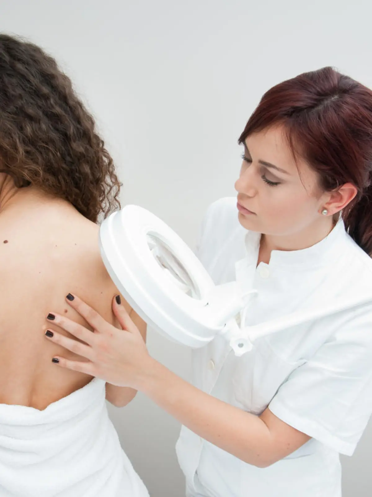 dermatologist doctor inspecting woman skin for moles and melanoma