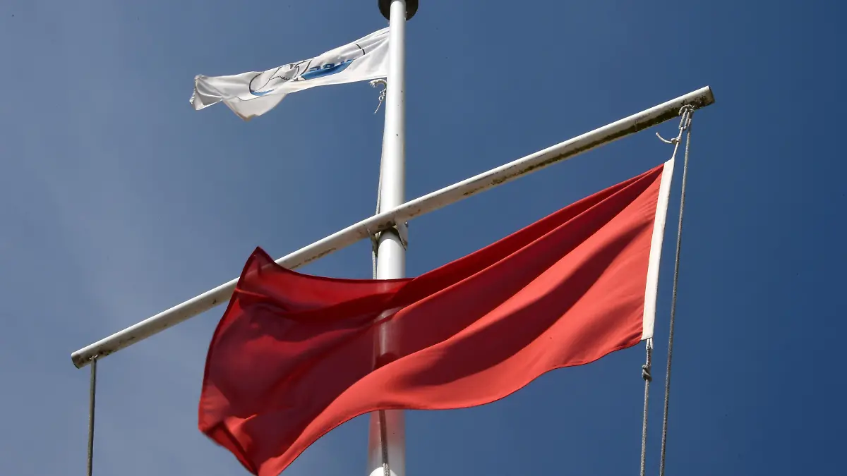 Die rote Flagge als Zeichen für das Badeverbot weht am 22.07.2014 am Ostseestrand von Timmendorfer Strand (Schleswig-Holstein). Wegen starker Strömung herrscht hier ein Badeverbot. Nach den tödlichen Badeunfällen an der Ostsee hat die Polizei an die Badegäste appelliert, rote Flaggen der DLRG und direkt am Wasser aufgestellte Hinweisschilder zu beachten. Foto: Carsten Rehder/dpa (Zu dpa"Polizei mahnt Badegäste nach Unfällen zur Besonnenheit" vom 22.07.2014)