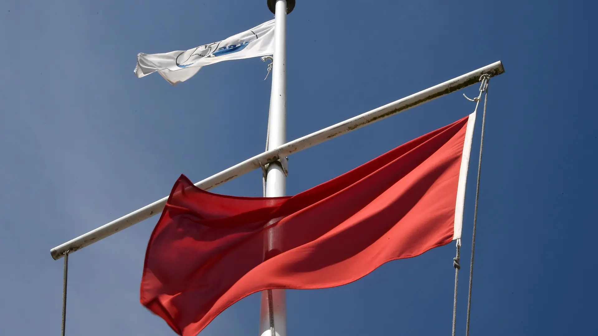 Die rote Flagge als Zeichen für das Badeverbot weht am 22.07.2014 am Ostseestrand von Timmendorfer Strand (Schleswig-Holstein). Wegen starker Strömung herrscht hier ein Badeverbot. Nach den tödlichen Badeunfällen an der Ostsee hat die Polizei an die Badegäste appelliert, rote Flaggen der DLRG und direkt am Wasser aufgestellte Hinweisschilder zu beachten. Foto: Carsten Rehder/dpa (Zu dpa"Polizei mahnt Badegäste nach Unfällen zur Besonnenheit" vom 22.07.2014)