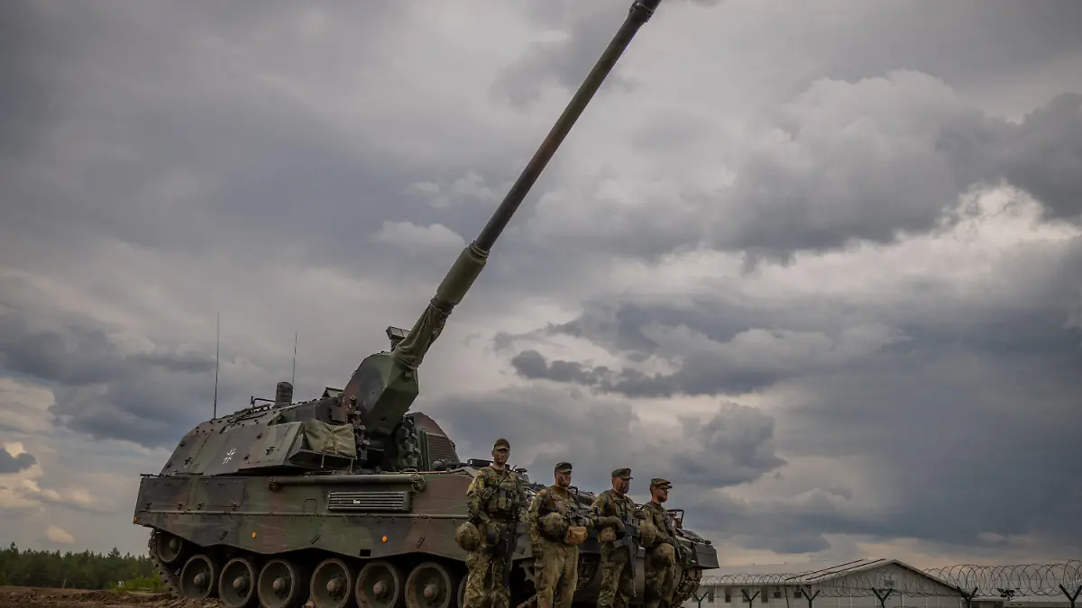 07.06.2022, Litauen, Pabrade: Soldaten stehen vor einem gepanzerten, selbstfahrenden Artilleriegeschütz vom Typ Panzerhaubitze 2000 der Bundeswehr, das von der NATO Enhanced Forward Presence Battle Group (eFP-Bataillon) eingesetzt wird, während des Besuchs von Bundeskanzler Scholz im Camp Adrian Rohn. Scholz hat Litauen zusätzliche militärische Unterstützung für die Verteidigung gegen einen möglichen russischen Angriff zugesagt. Foto: Michael Kappeler/dpa +++ dpa-Bildfunk +++