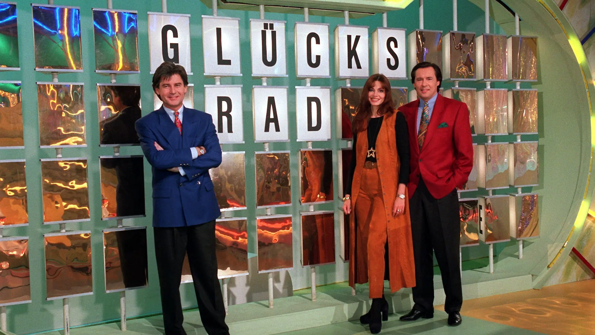 Das "Glücksrad"-Team (l-r): Frederic Meisner, Maren Gilzer und Peter Bond am 10. Februar 1994 vor der Buchstaben-Rätselwand in Berlin-Adlershof.
