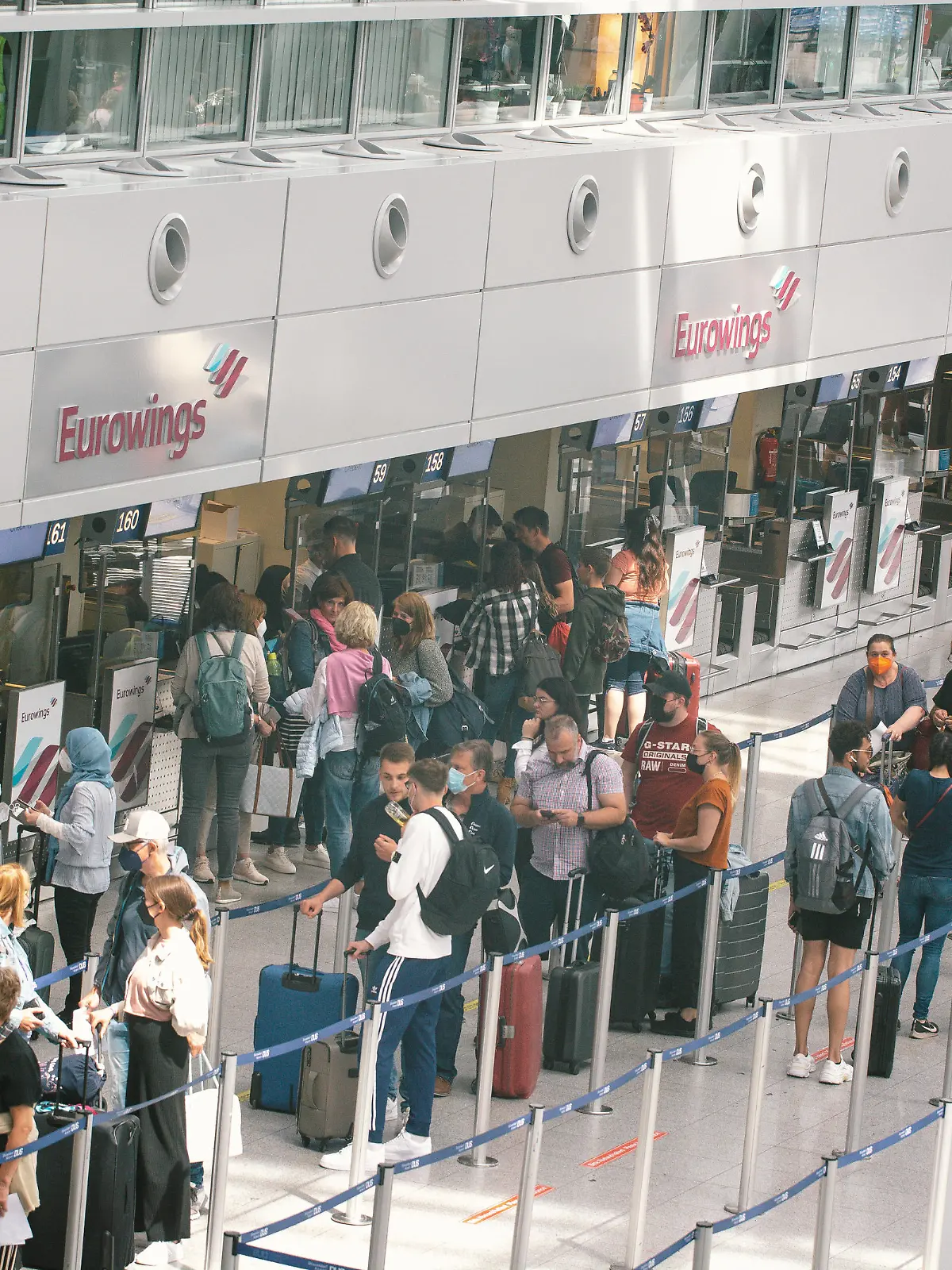 people wait in a long line in front of Eurowings Airline checkin counter at Duesseldorf airport on June 3, 2022 before the Pentecost holiday weekend. (Photo by Ying Tang/NurPhoto)