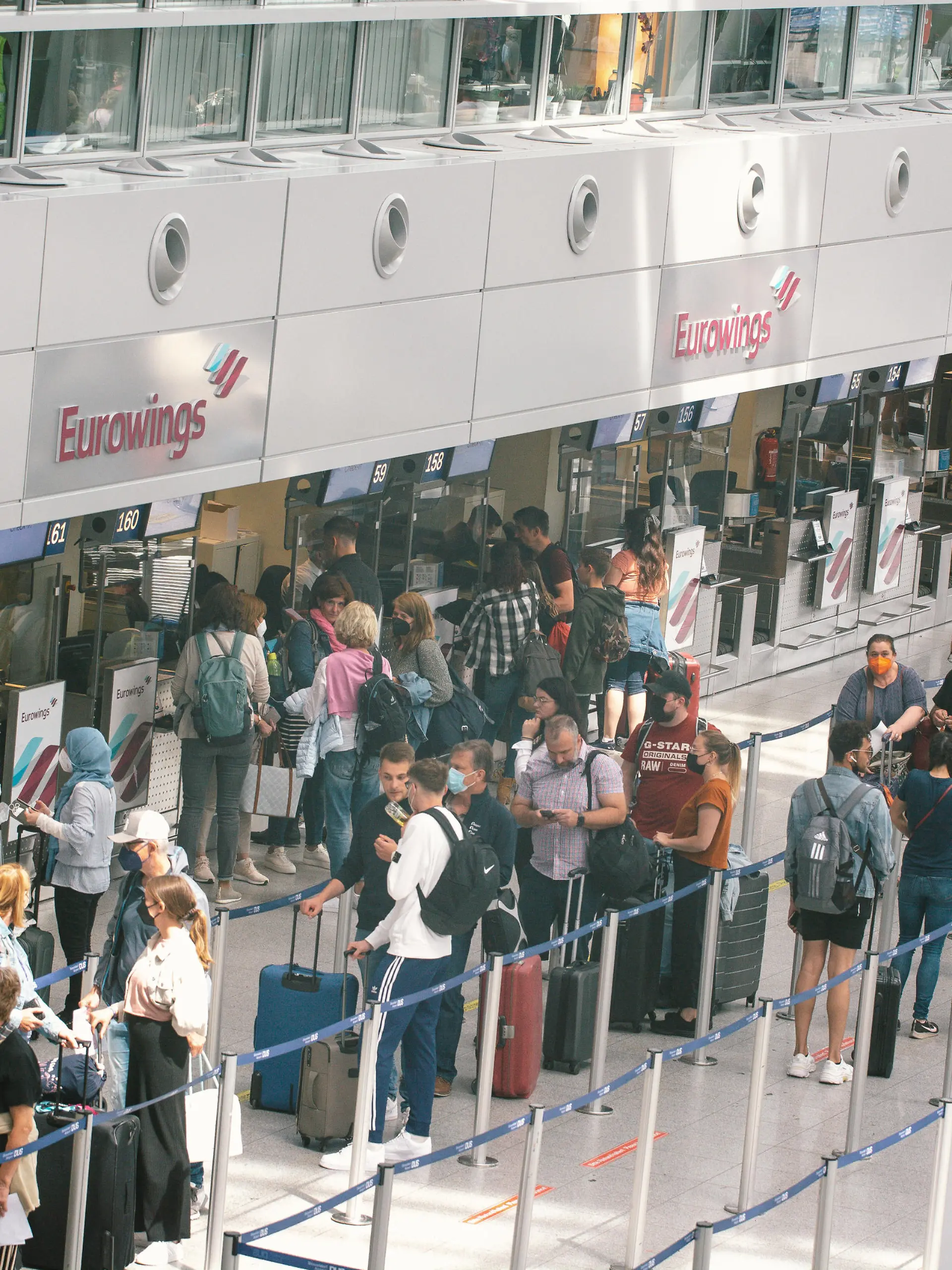 people wait in a long line in front of Eurowings Airline checkin counter at Duesseldorf airport on June 3, 2022 before the Pentecost holiday weekend. (Photo by Ying Tang/NurPhoto)