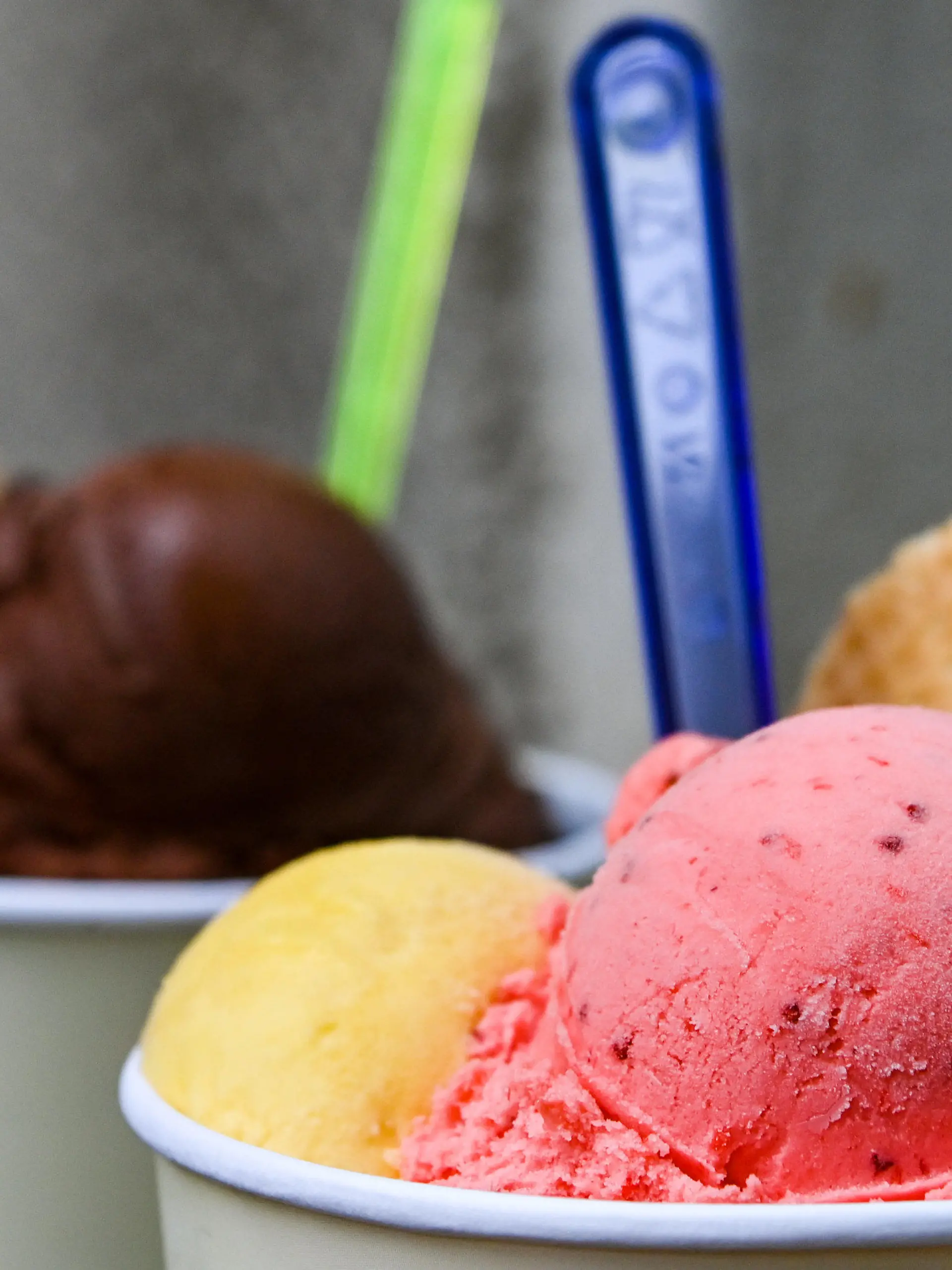 PRODUKTION - 24.05.2022, Berlin: Eisbecher mit Kugeln verschiedener Sorten Eis stehen auf einem Tisch in der Eisdiele «Eiskultur» in Schöneweide. Eiscreme und Sorbet gehören für viele Deutsche zum Sommer dazu. Jährlich werden neue Geschmacksrichtungen zum Trend ausgerufen. Viele bleiben dennoch lieber klassisch bei Vanille, Schoko und Erdbeer. (Zu dpa: «Sommertrends '22: Fischerhüte in, Füßlinge out?») Foto: Jens Kalaene/dpa +++ dpa-Bildfunk +++