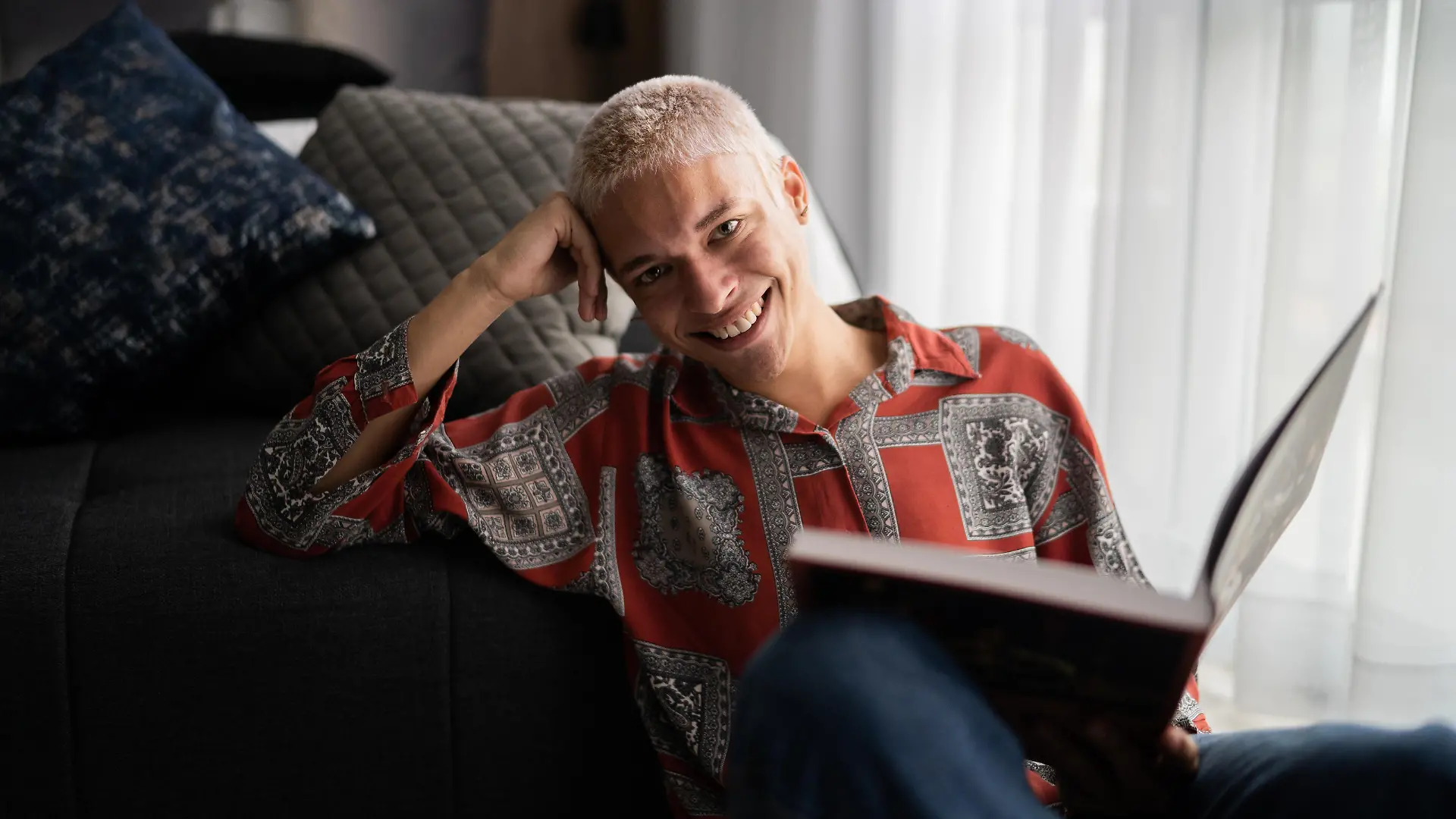 Portrait of a happy young man reading at home