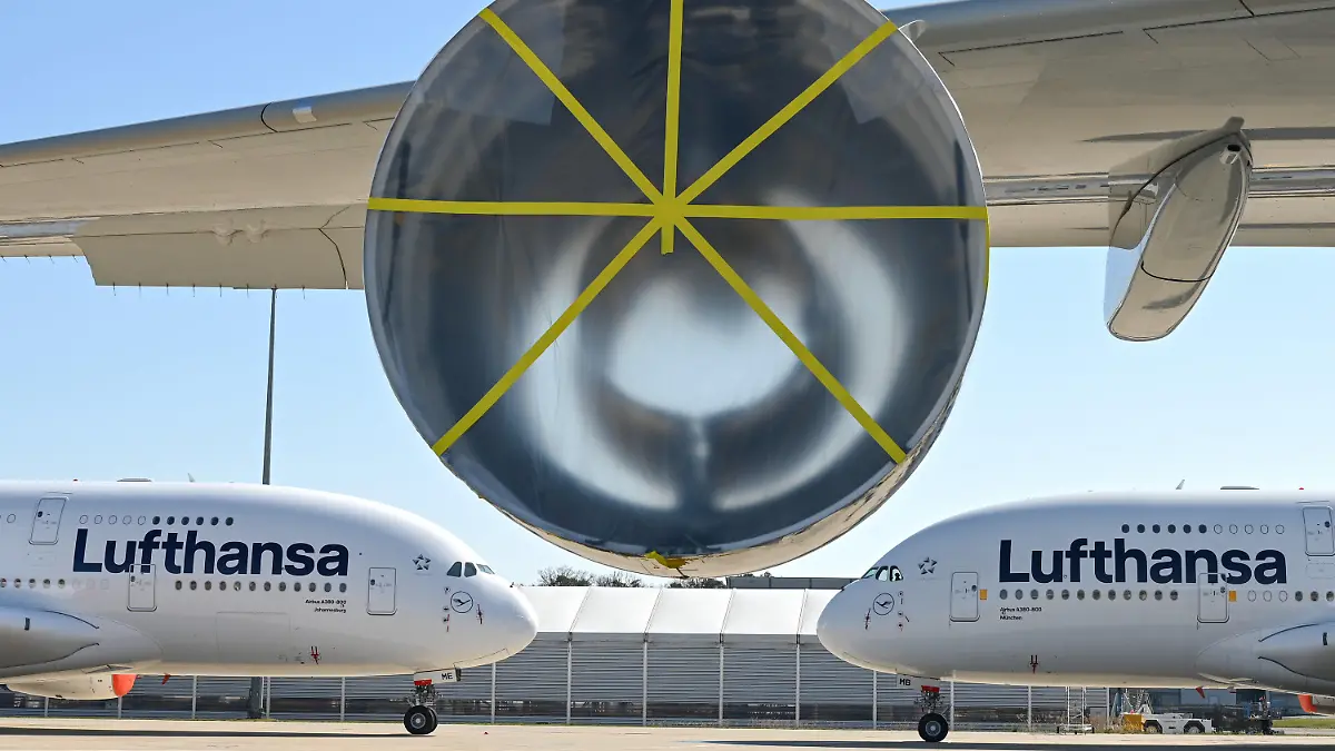 ARCHIV - 23.03.2020, Hessen, Frankfurt/Main: Zwei Airbus A380-800 der Lufthansa sind auf dem Gelände der Lufthansa Technik am Frankfurter Flughafen hinter einem A380 geparkt, an dem ein Triebwerk ausgebaut worden war. Die Lufthansa hatte damals damit begonnen, in der Coronavirus-Krise überflüssige Flugzeuge am Frankfurter Flughafen zur parken. Die Lufthansa muss in der Corona-Krise noch stärker schrumpfen als bislang geplant. Mindestens 150 Flugzeuge der einstmals 760 Jets umfassenden Konzernflotte werden dauerhaft nicht mehr abheben. (Zu dpa "Lufthansa will härter sparen - A 380 werden eingemottet") Foto: Arne Dedert/dpa Pool/dpa +++ dpa-Bildfunk +++
