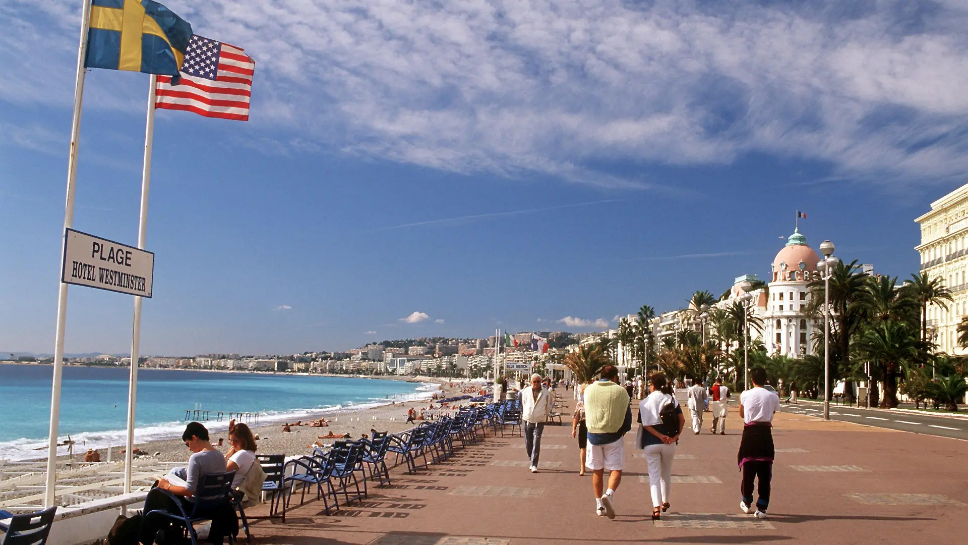 Passanten flanieren auf der Promenade des Anglais in Nizza an der französischen Riviera. Im Hintergrund rechts das Hotel Negresco. (Aufnahme von 2001).