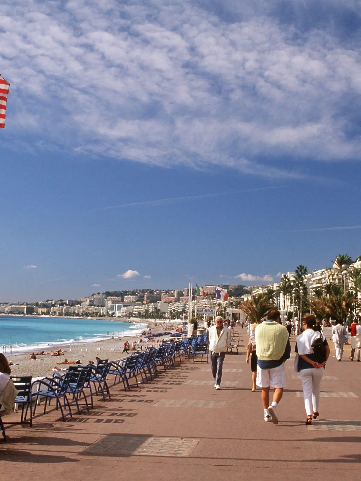 Passanten flanieren auf der Promenade des Anglais in Nizza an der französischen Riviera. Im Hintergrund rechts das Hotel Negresco. (Aufnahme von 2001).