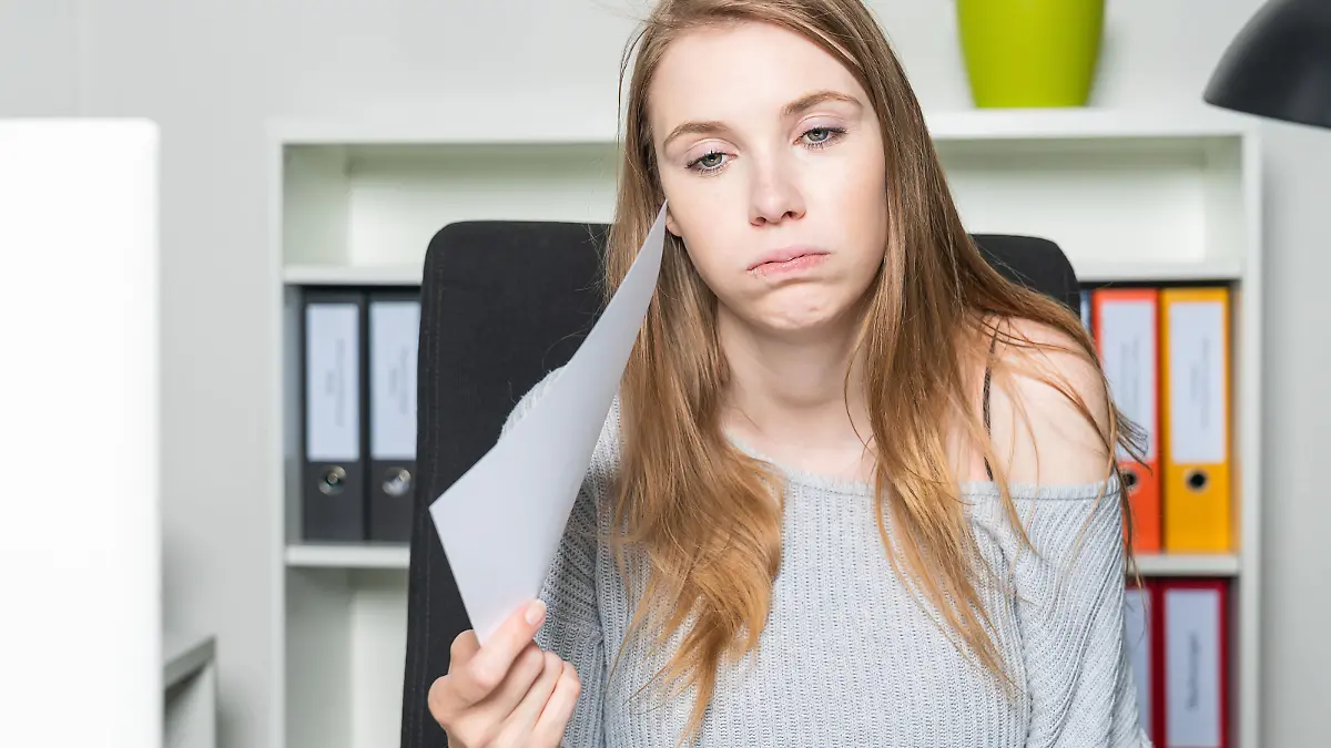 A woman in the office is waving her head with a sheet of paper