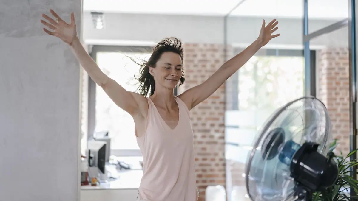 Businesswoman in office enjoying breeze from a fan model released Symbolfoto property released PUBLICATIONxINxGERxSUIxAUTxHUNxONLY KNSF02051  