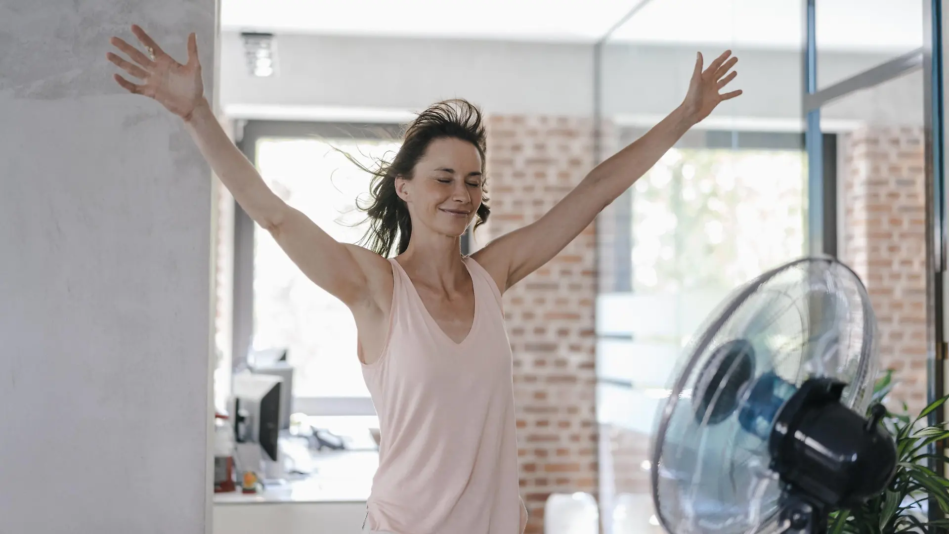Businesswoman in office enjoying breeze from a fan model released Symbolfoto property released PUBLICATIONxINxGERxSUIxAUTxHUNxONLY KNSF02051