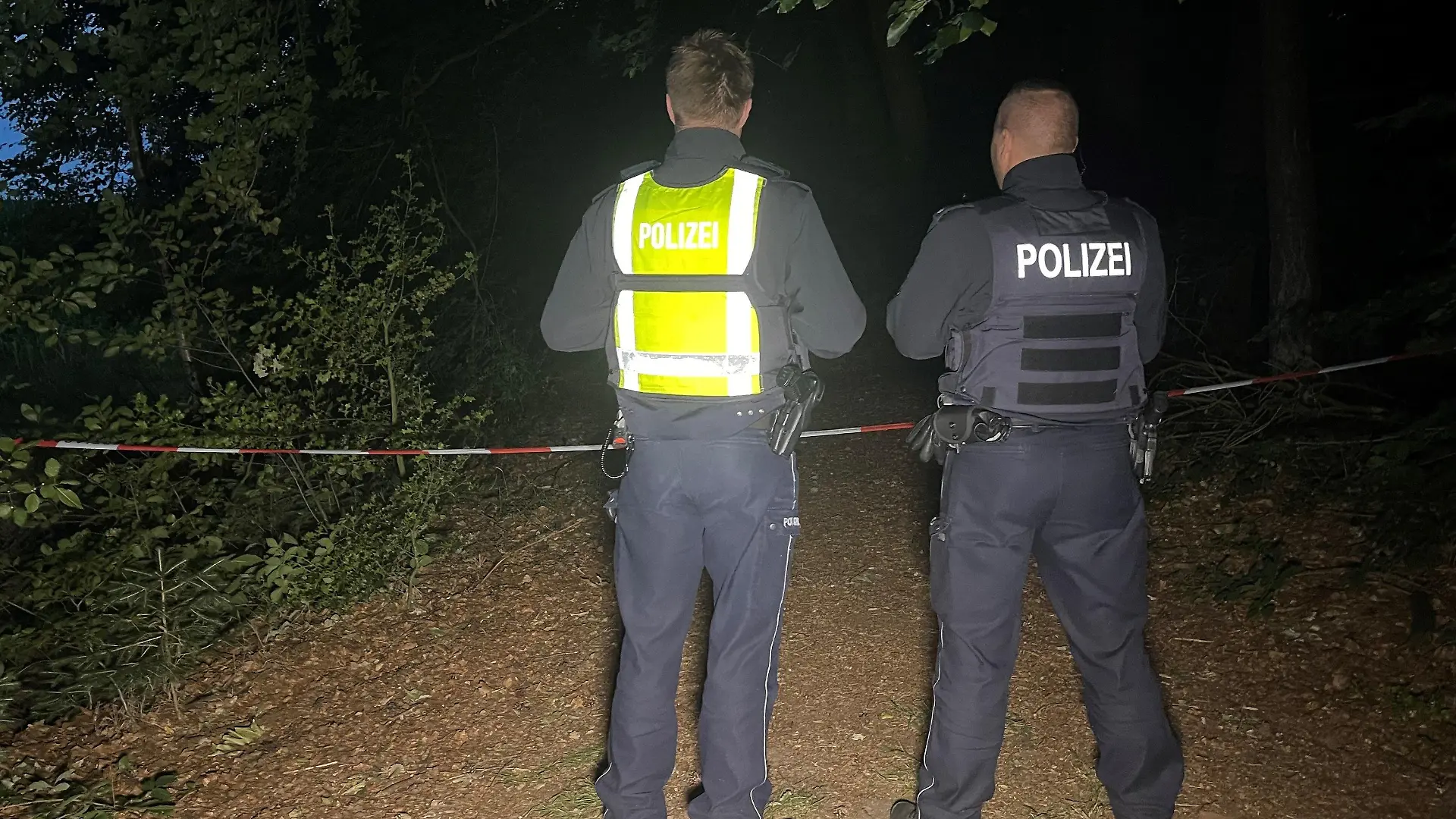 16.07.2023, Nordrhein-Westfalen, Halle: Polizisten stehen an einem abgesperrten Waldstück zwischen Halle-Kölkebeck undd Hesselteich, einem Ortsteil von Versmold. Spaziergänger hatten in dem Waldstück im Kreis Gütersloh eine Leiche gefunden. Die weiteren Ermittlungen zur Feststellung der Identität sowie der Todesursache übernahm eine Mordkommission des Polizeipräsidiums Bielefeld. Foto: Christian Müller/Westfalennews/dpa +++ dpa-Bildfunk +++