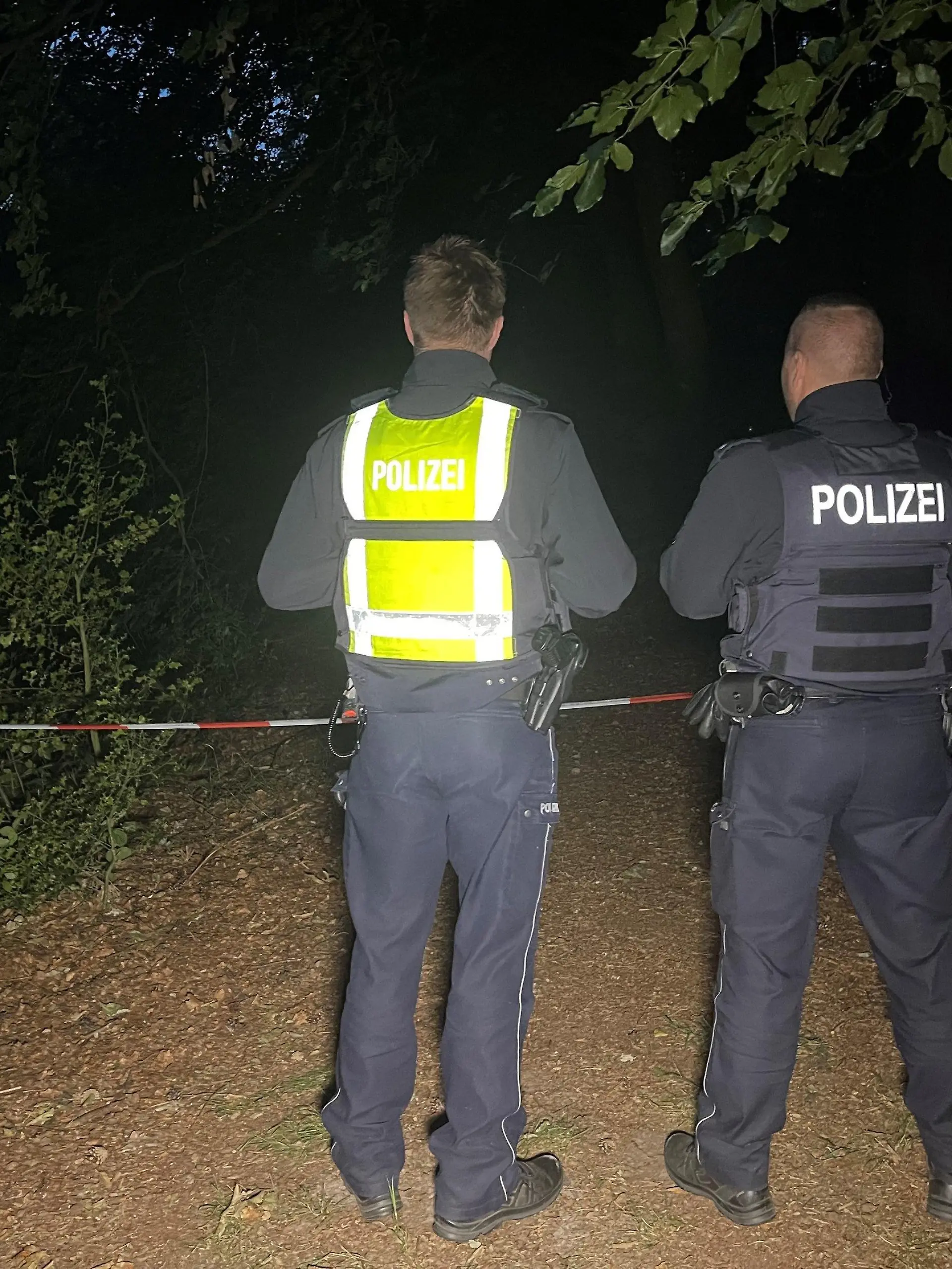 16.07.2023, Nordrhein-Westfalen, Halle: Polizisten stehen an einem abgesperrten Waldstück zwischen Halle-Kölkebeck undd Hesselteich, einem Ortsteil von Versmold.  Spaziergänger hatten in dem Waldstück im Kreis Gütersloh eine Leiche gefunden. Die weiteren Ermittlungen zur Feststellung der Identität sowie der Todesursache übernahm eine Mordkommission des Polizeipräsidiums Bielefeld. Foto: Christian Müller/Westfalennews/dpa +++ dpa-Bildfunk +++