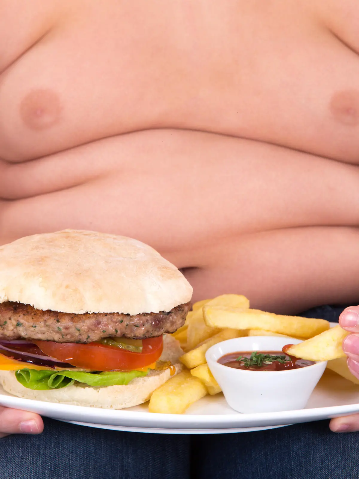 The boy eating a hamburger and french fries on white backround