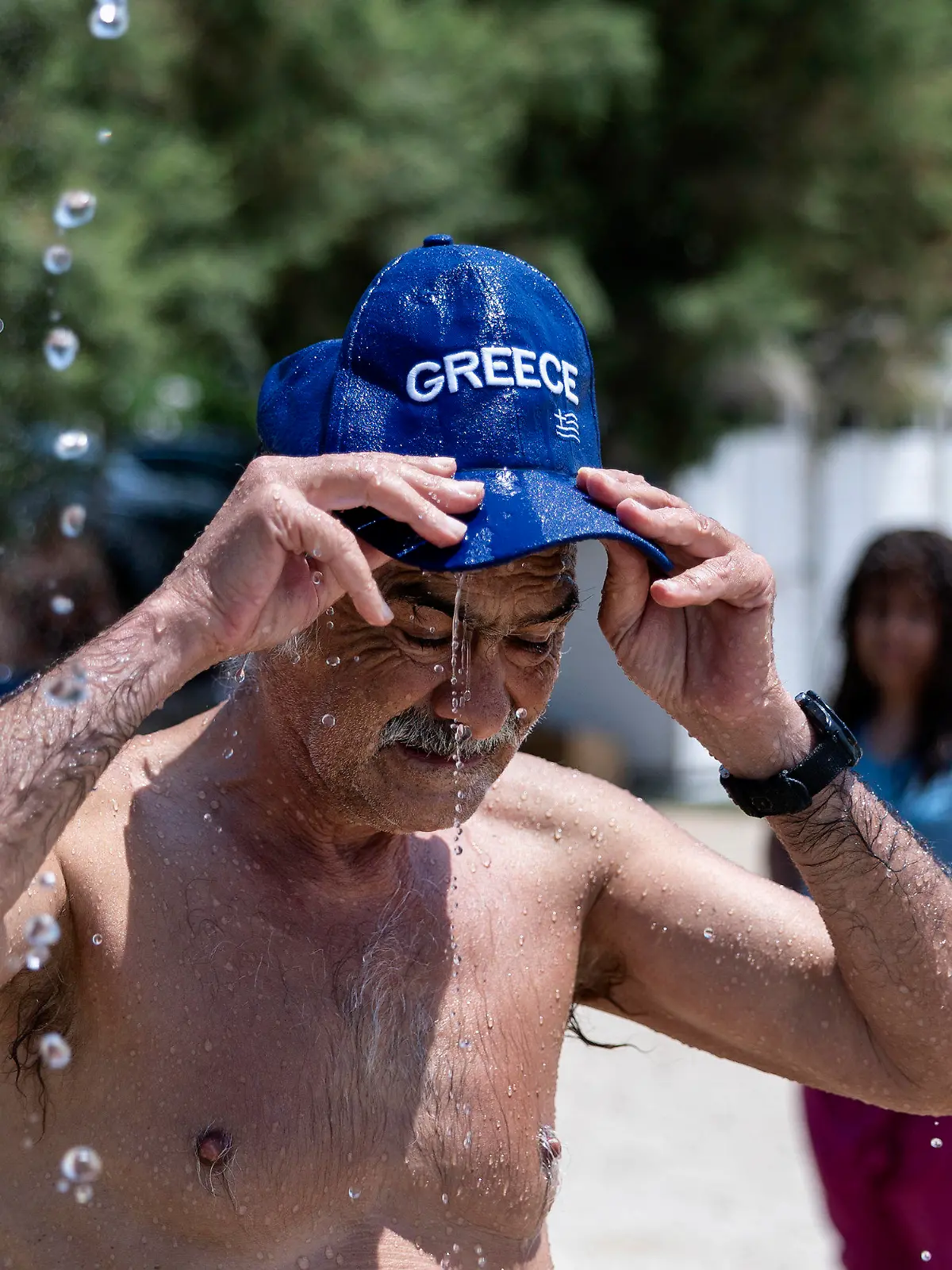 15.07.2023, Griechenland, Athen: Ein Strandbesucher kühlt sich unter einer Dusche im Vorort Alimos in Athen ab. Griechenland befindet sich auf dem Höhepunkt der aktuellen Hitzewelle - die Wetterstationen im Land verzeichneten bereits am Freitag Werte über 40 Grad. Foto: Yorgos Karahalis/AP/dpa +++ dpa-Bildfunk +++