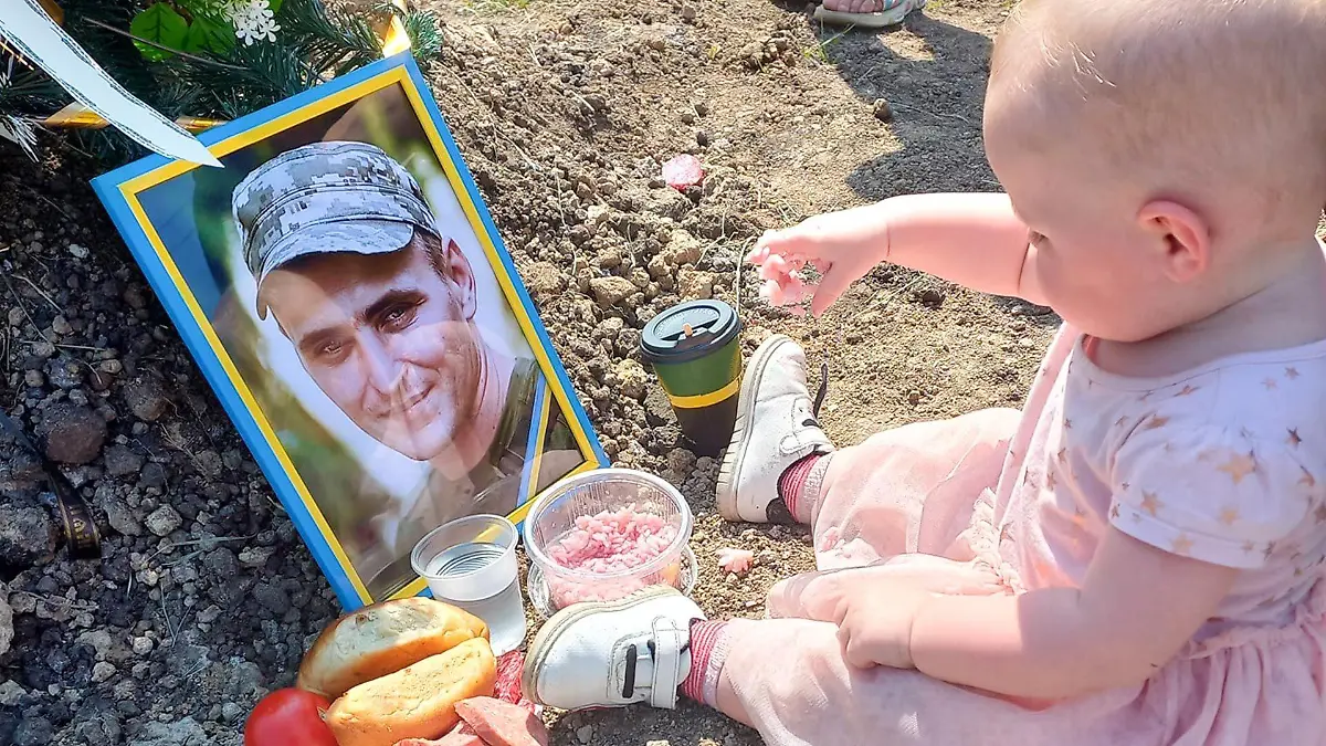 Ein Mädchen sitzt an seinem Geburtstag am Grab seines ukrainischen Vaters und frühstückt.