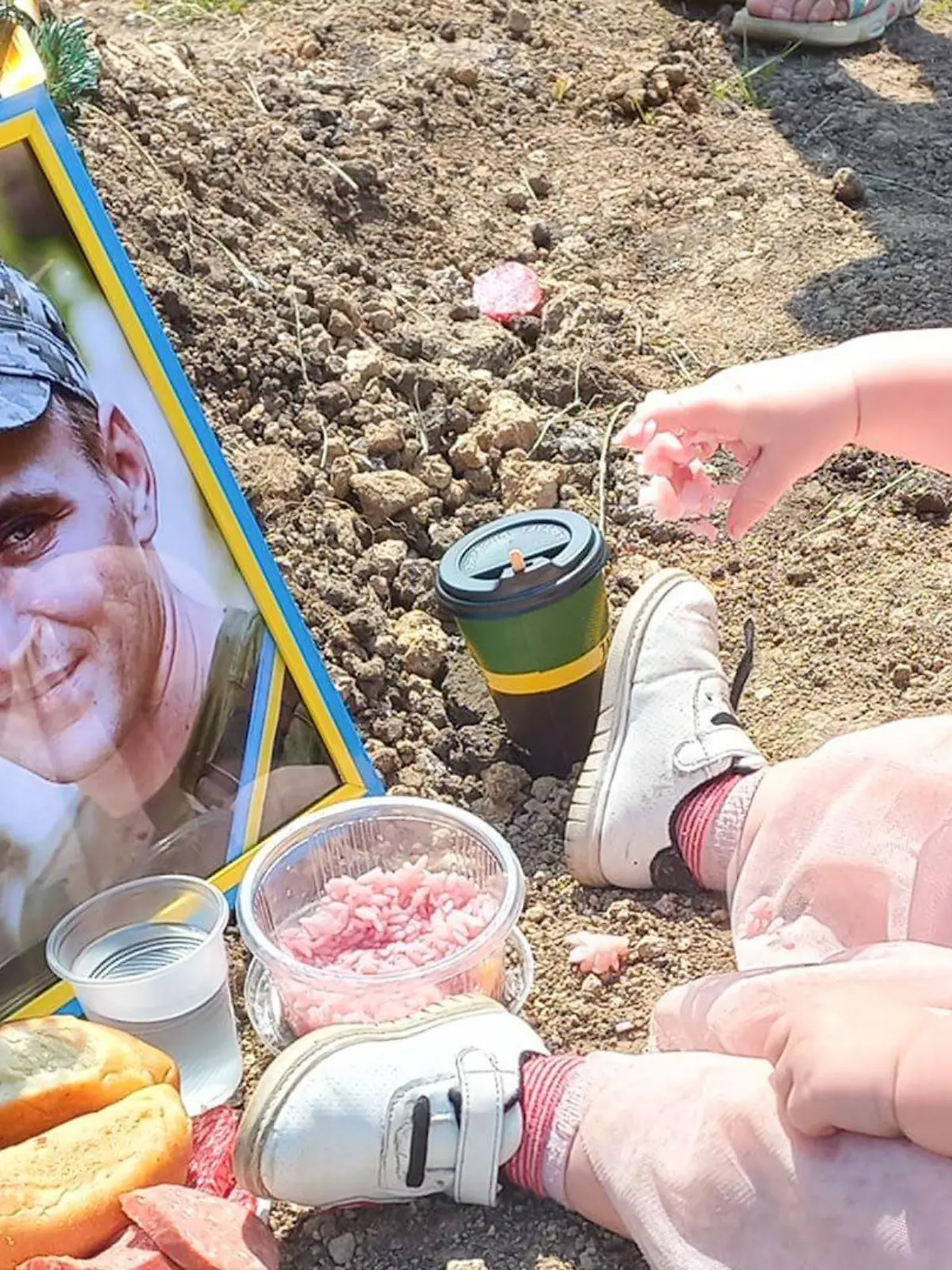 Ein Mädchen sitzt an seinem Geburtstag am Grab seines ukrainischen Vaters und frühstückt.